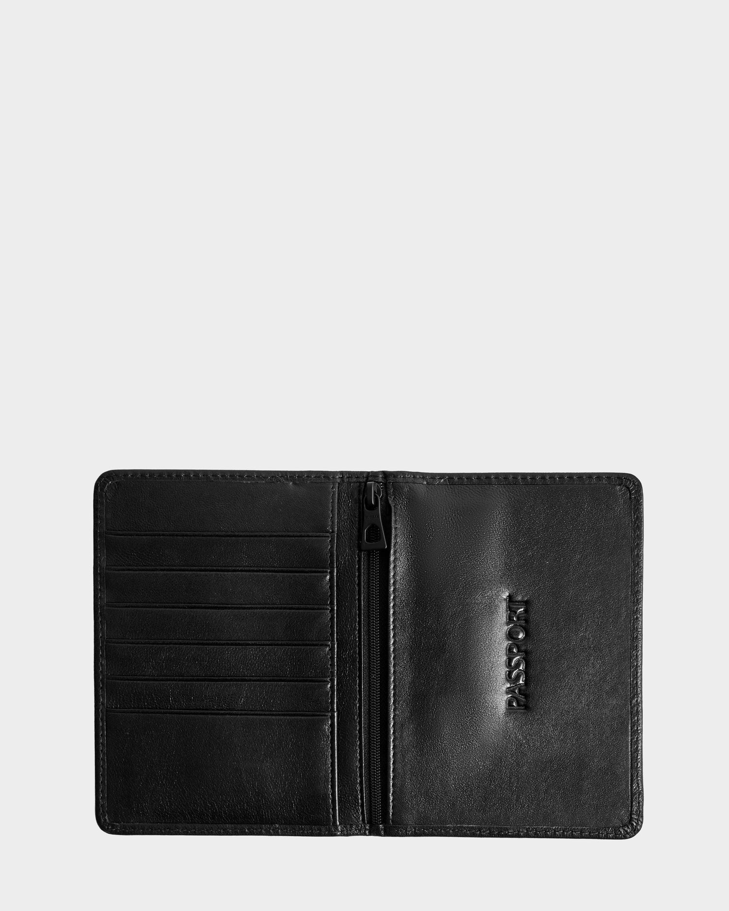 The Rudsak ROBIN - 9425562 Black passport holder is shown open, with card slots on the left, a center zip pocket, and PASSPORT embossed on the right side.