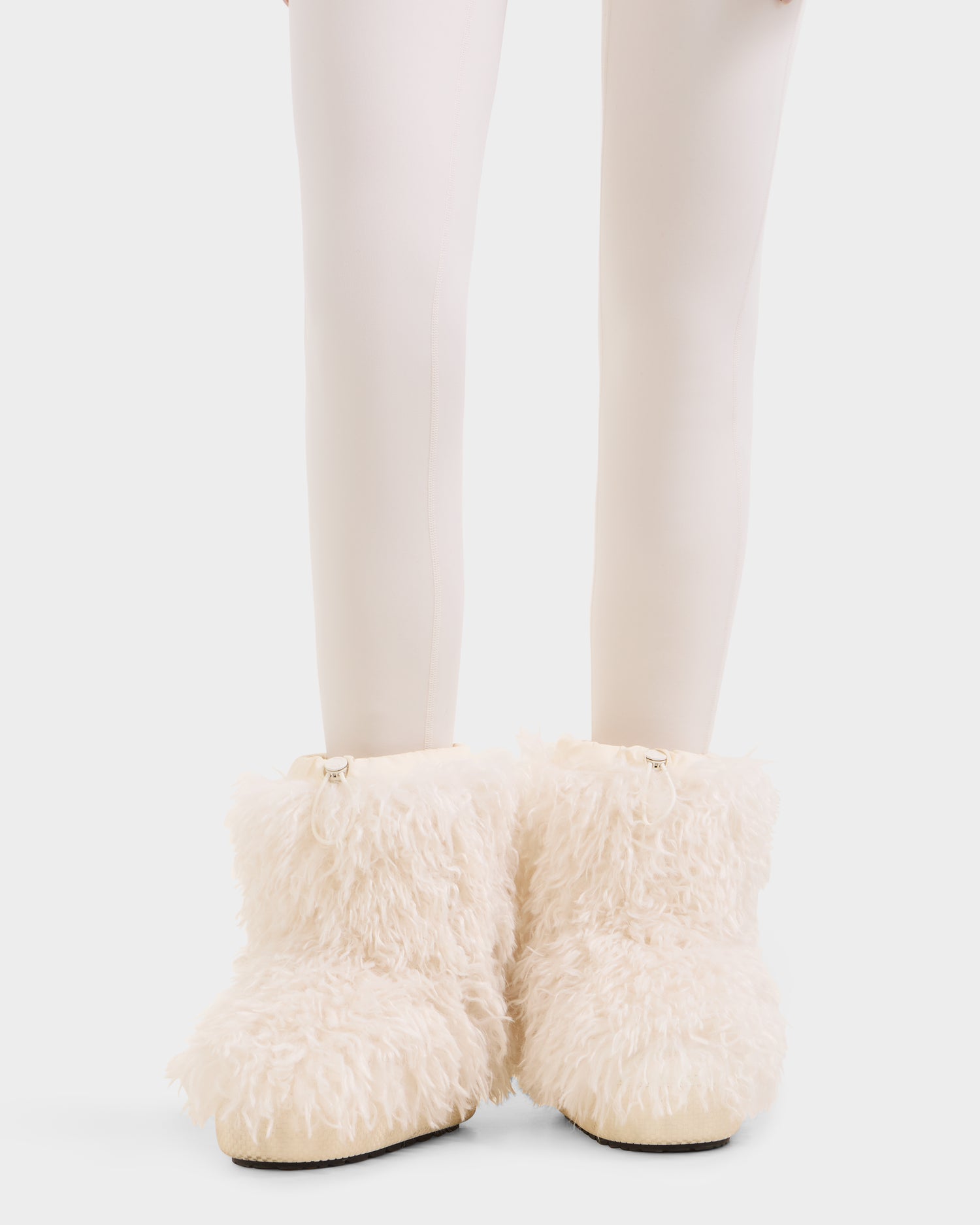 A person in white tights wears Rudsak's ROSSY - 8224518 Iceland fluffy, cream-colored faux Mongolian fur boots, featuring a shaggy texture and cozy look—ideal for women's winter style.