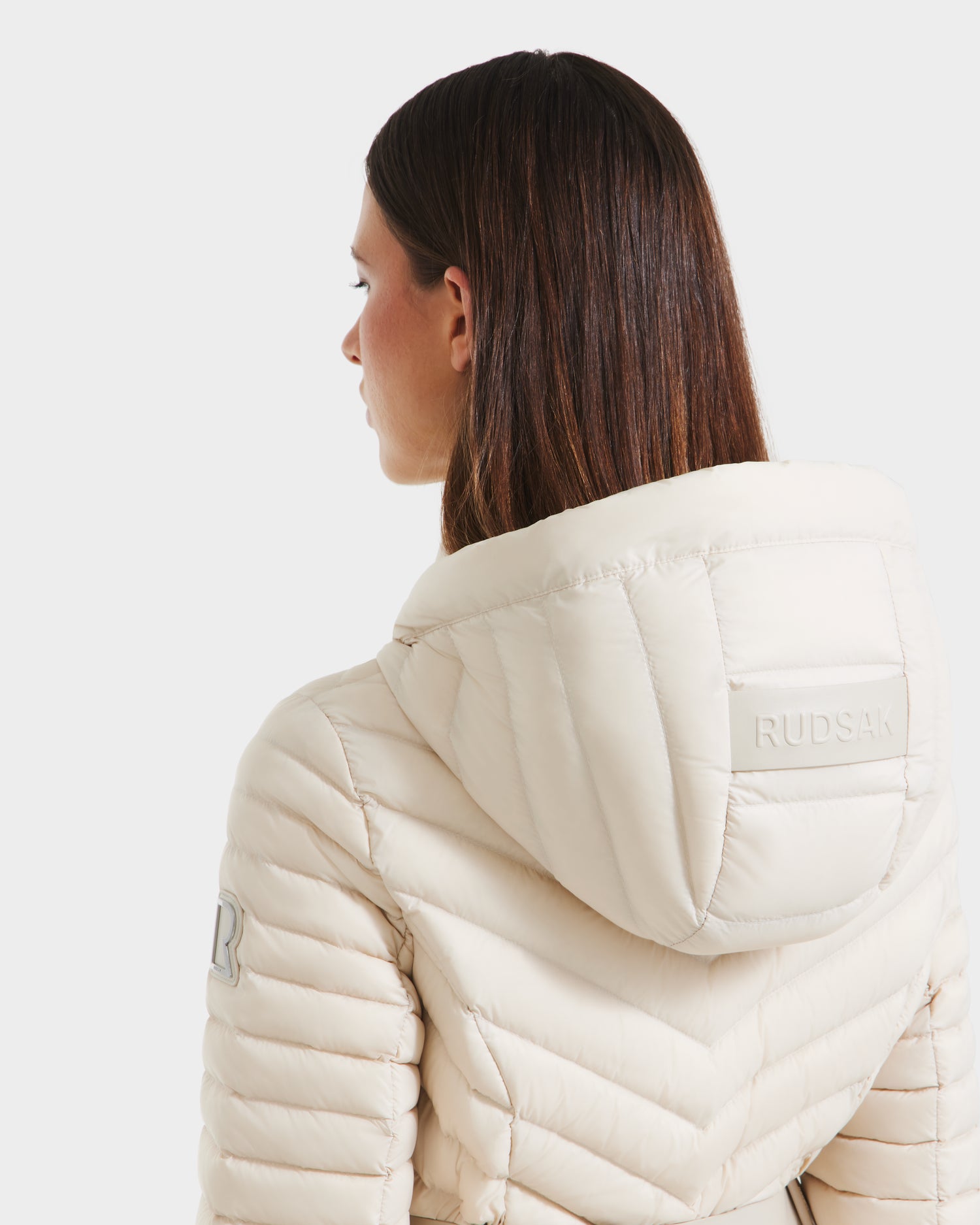 A woman wearing the Rudsak SCARLETT - 8125004 Vanilla, a womens lightweight down jacket in a crisp white coat style.