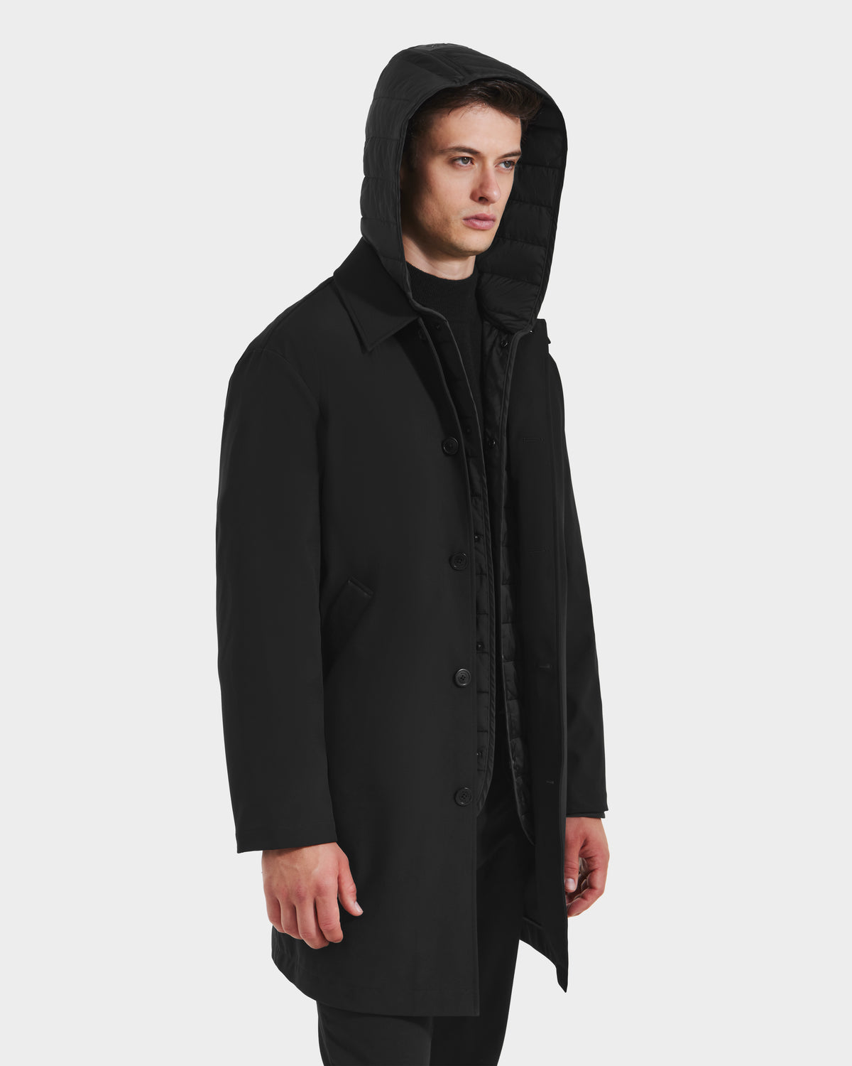A young man in the Rudsak STANTON - 6125531 Black weather-resistant hooded coat stands against a plain white background, facing slightly to the side with a neutral expression.