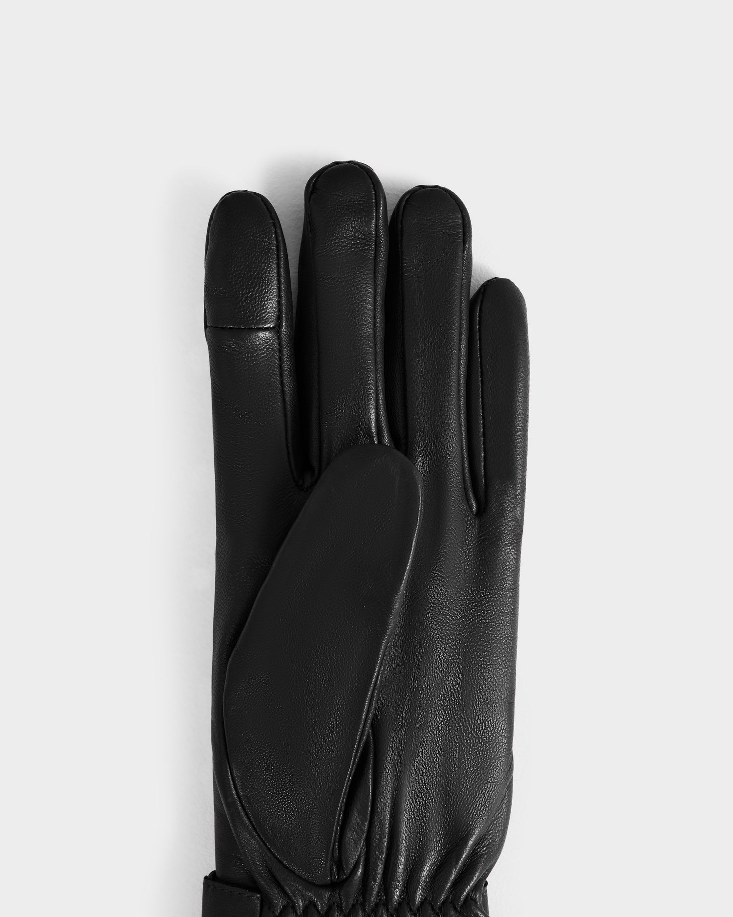 The Rudsak STROMBOLI - 8424510 Black is a women’s black leather glove with a gathered wrist, shown on a plain light gray background. It is cashmere lined for added warmth and comfort.