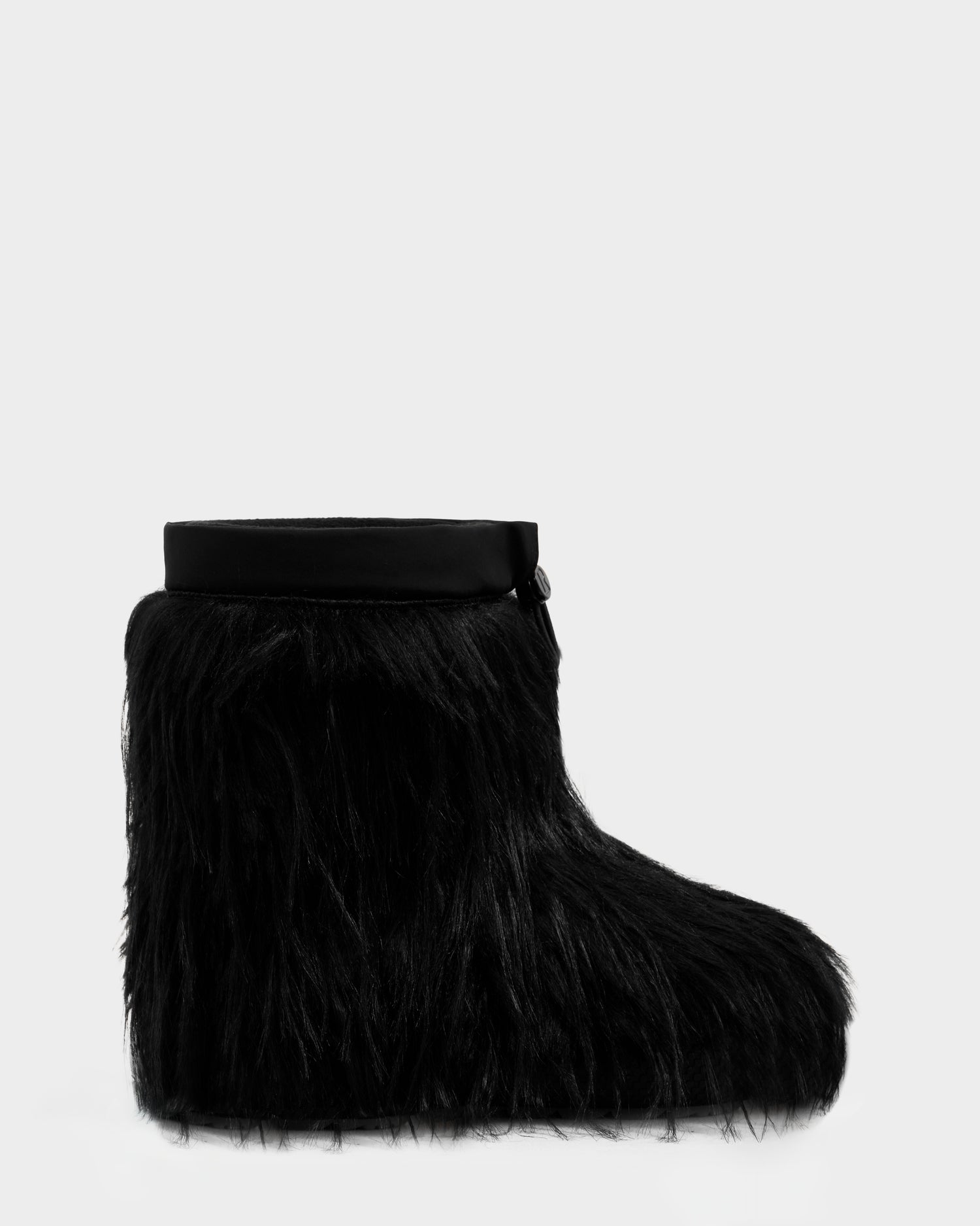 The SUZIE G - 8225545 Black by Rudsak is a black moon boot with long, shaggy faux fur and a smooth black band around the ankle, shown in profile against a plain white background.