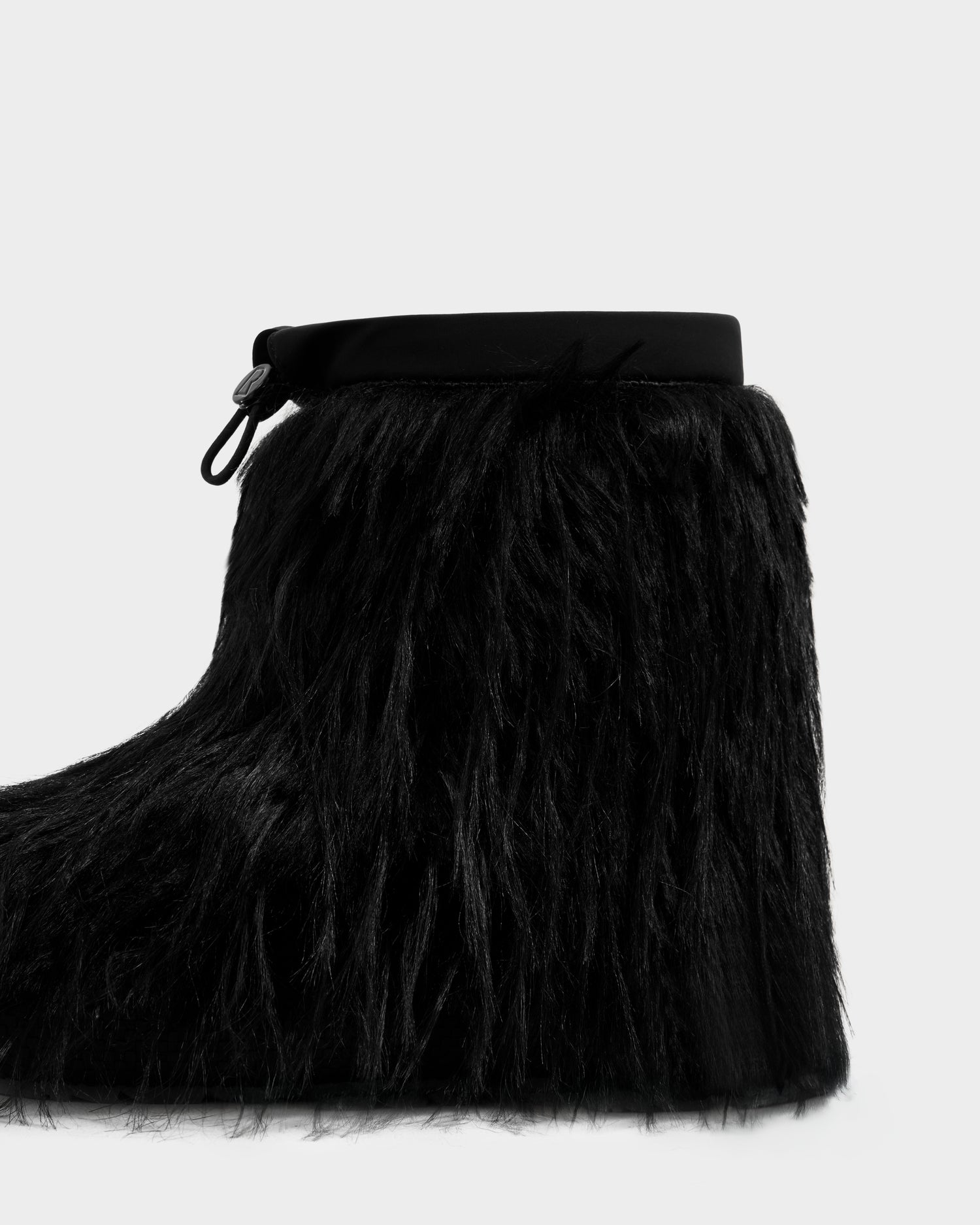 The SUZIE G - 8225545 Black by Rudsak is a women’s moon boot in long black faux fur with a smooth band and drawstring closure—stylish après-ski winter boots.
