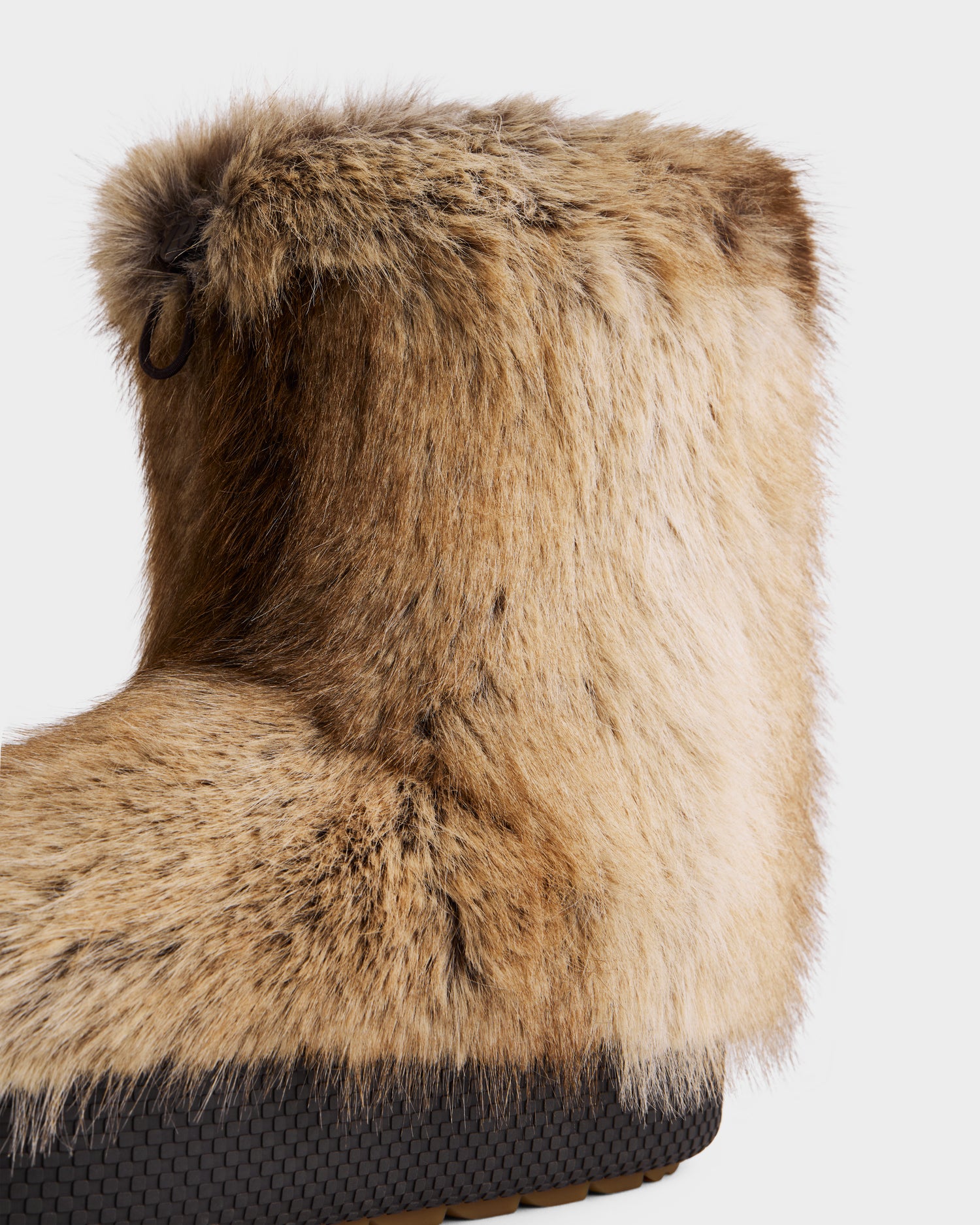 A close-up of the Rudsak SUZIE - 8225052 Mix Mocha women’s faux fur moon boot in tan and brown with a black textured rubber sole, shown against a plain white background.