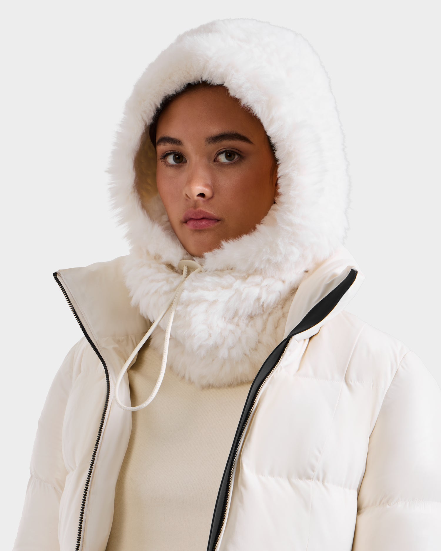 Wearing the Rudsak TARA - 8425025 Iceland jacket and a women’s faux fur balaclava, a person looks neutrally at the camera against a plain background, highlighting chic winter style.