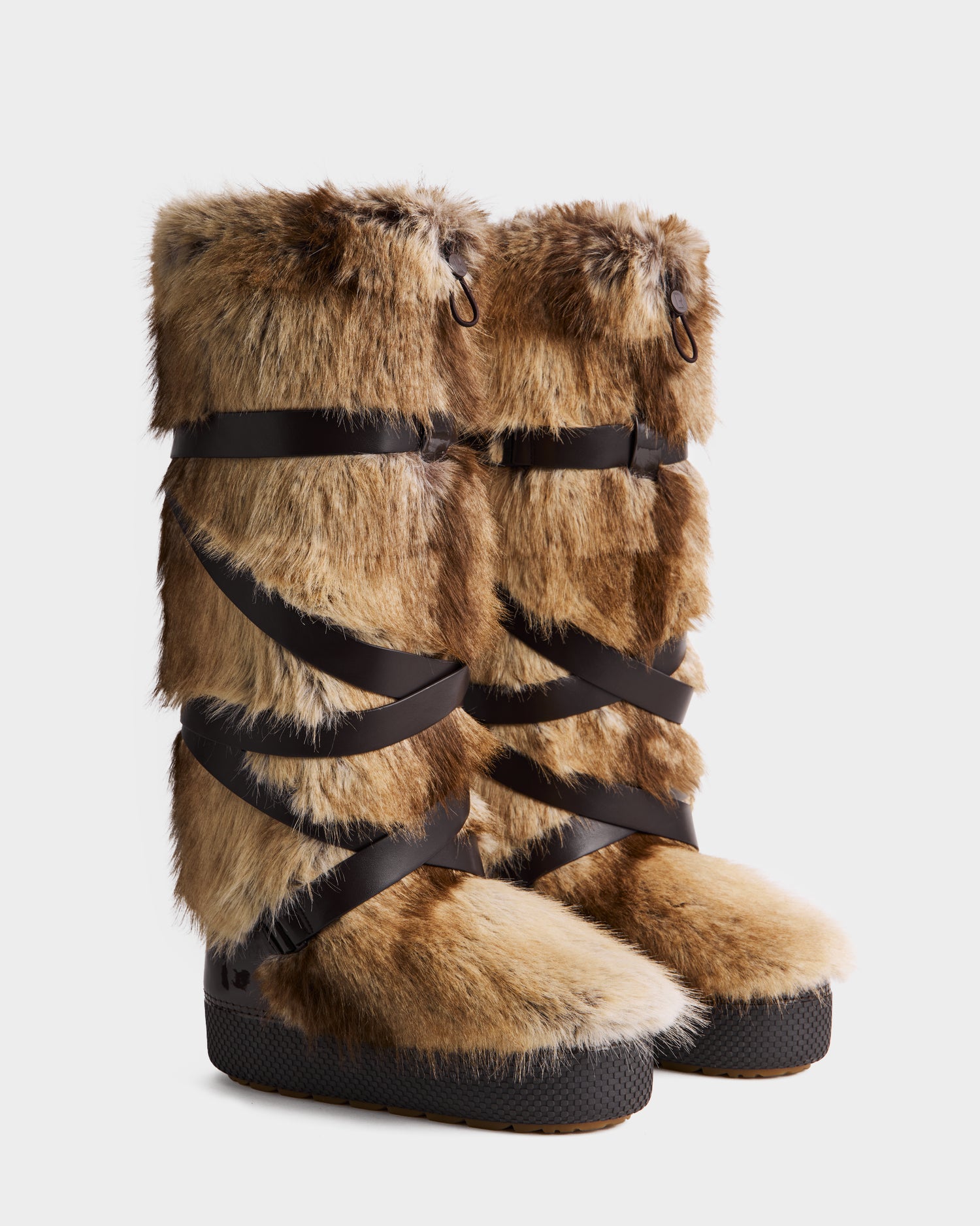 A pair of Rudsak TORIN - 8225029 Mix Mocha tall women’s faux fur moon boots in light brown and beige with black crisscross straps and thick textured black soles, displayed on a white background—ideal après-ski winter style.