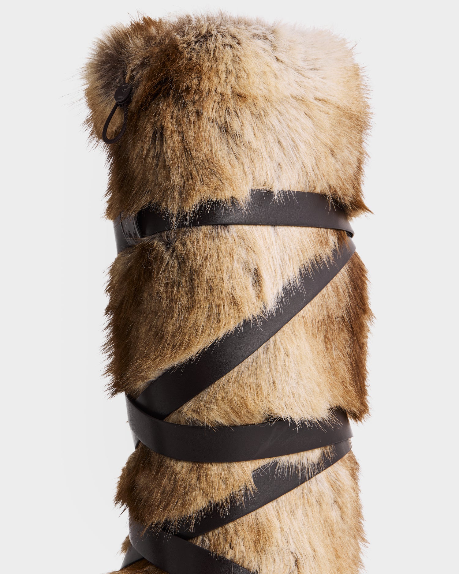 The TORIN - 8225029 Mix Mocha by Rudsak is a tall women’s moon boot in brown faux fur with a dark brown leather strap spiraling down, perfect for après-ski style, shown against a plain white background.