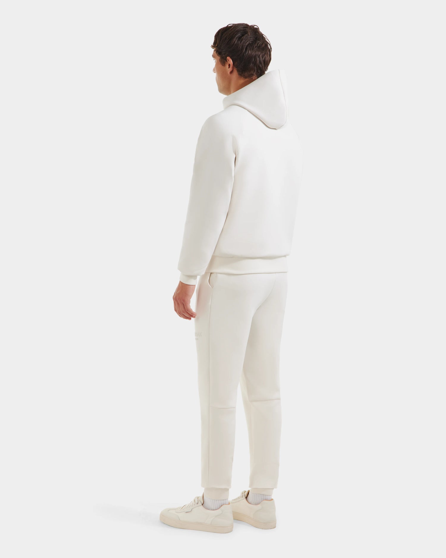 A man, seen from behind, wears the Rudsak TREVIS - 6525599 Vanilla cotton-blend hoodie and matching joggers with white sneakers, set against a plain white background.