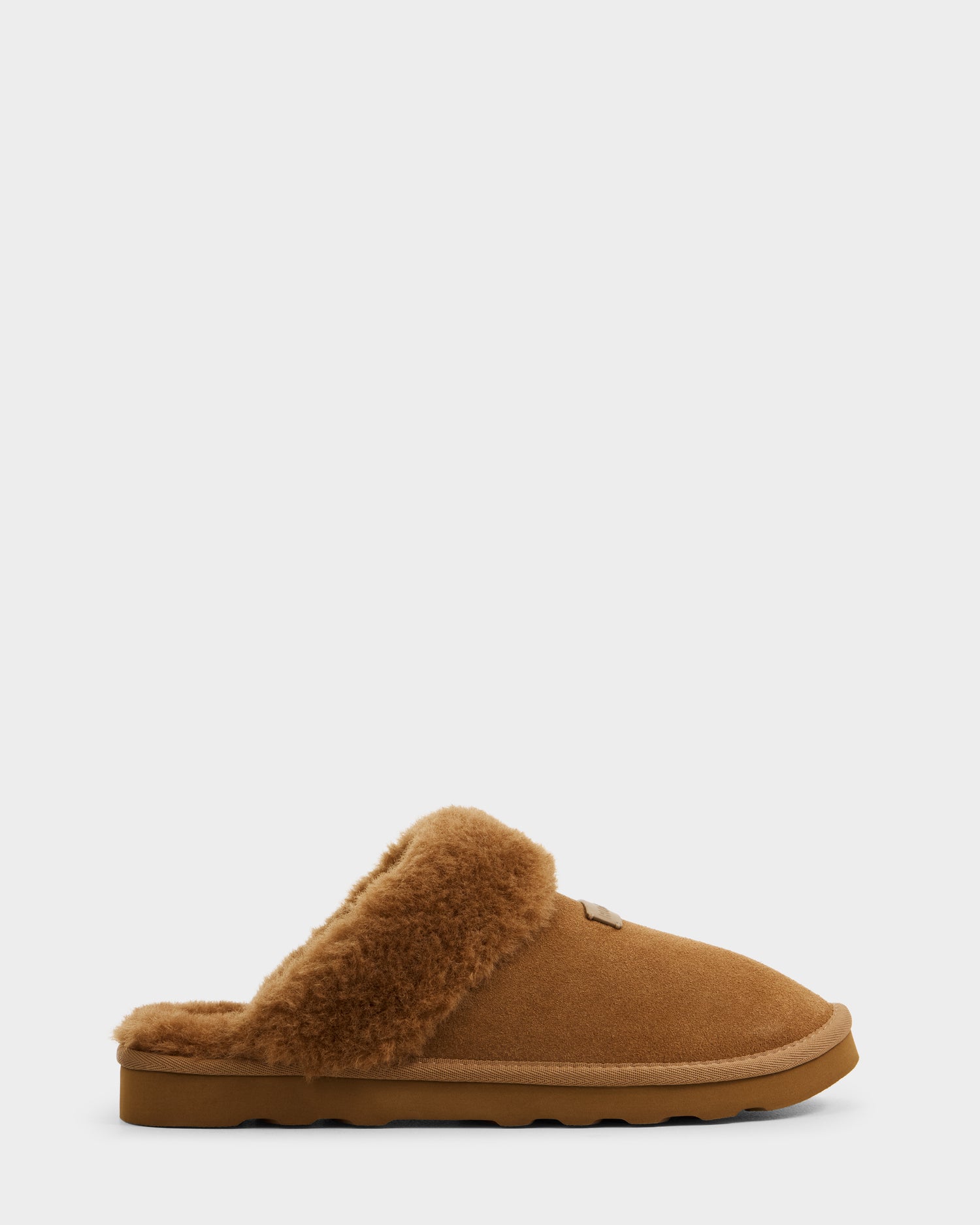The Rudsak WILBER - 6225509 Tan men’s suede slipper is shown in side profile against a white background, highlighting its plush shearling-lined interior and flat rubber sole.