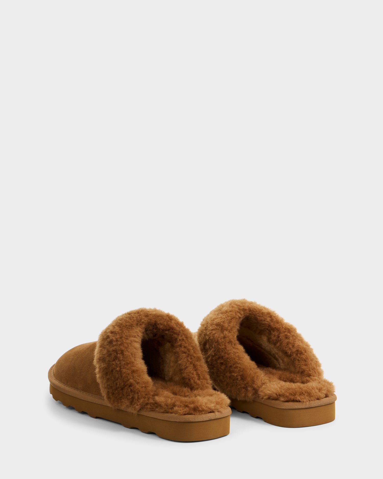 A pair of Rudsak WILBER - 6225509 Tan men’s slippers with soft suede and shearling-like lining, shown from the back and slightly side on a white background.