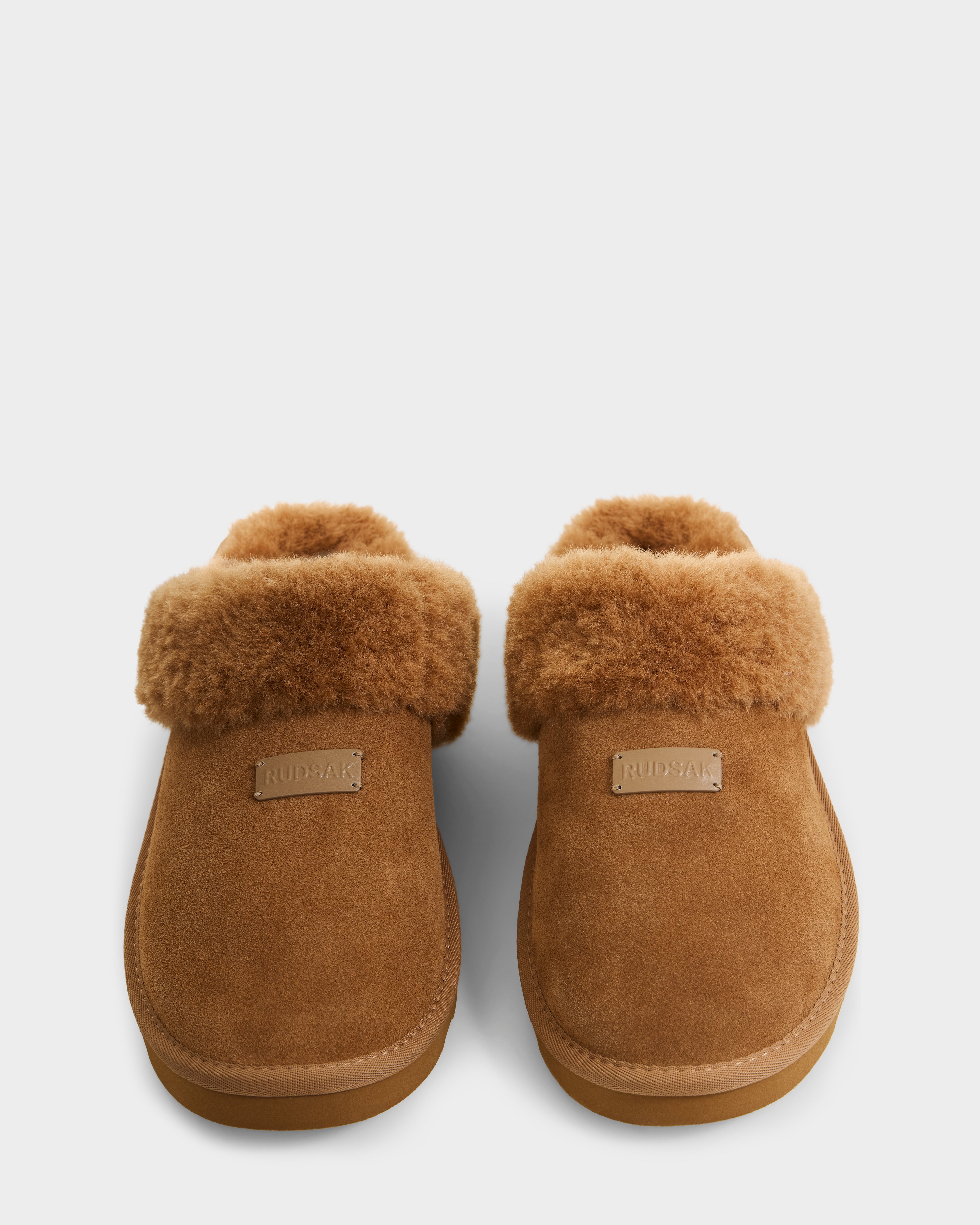 A pair of Rudsak WILBER - 6225509 Tan men’s suede slippers with plush faux shearling lining and folded cuffs, shown side by side on a plain white background. 