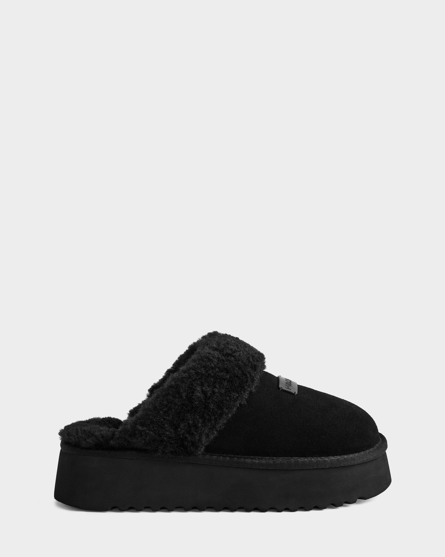 The WILMA - 8225582 Black by Rudsak is a black suede slipper with thick faux shearling lining and a chunky sole, shown in profile against a plain white background.