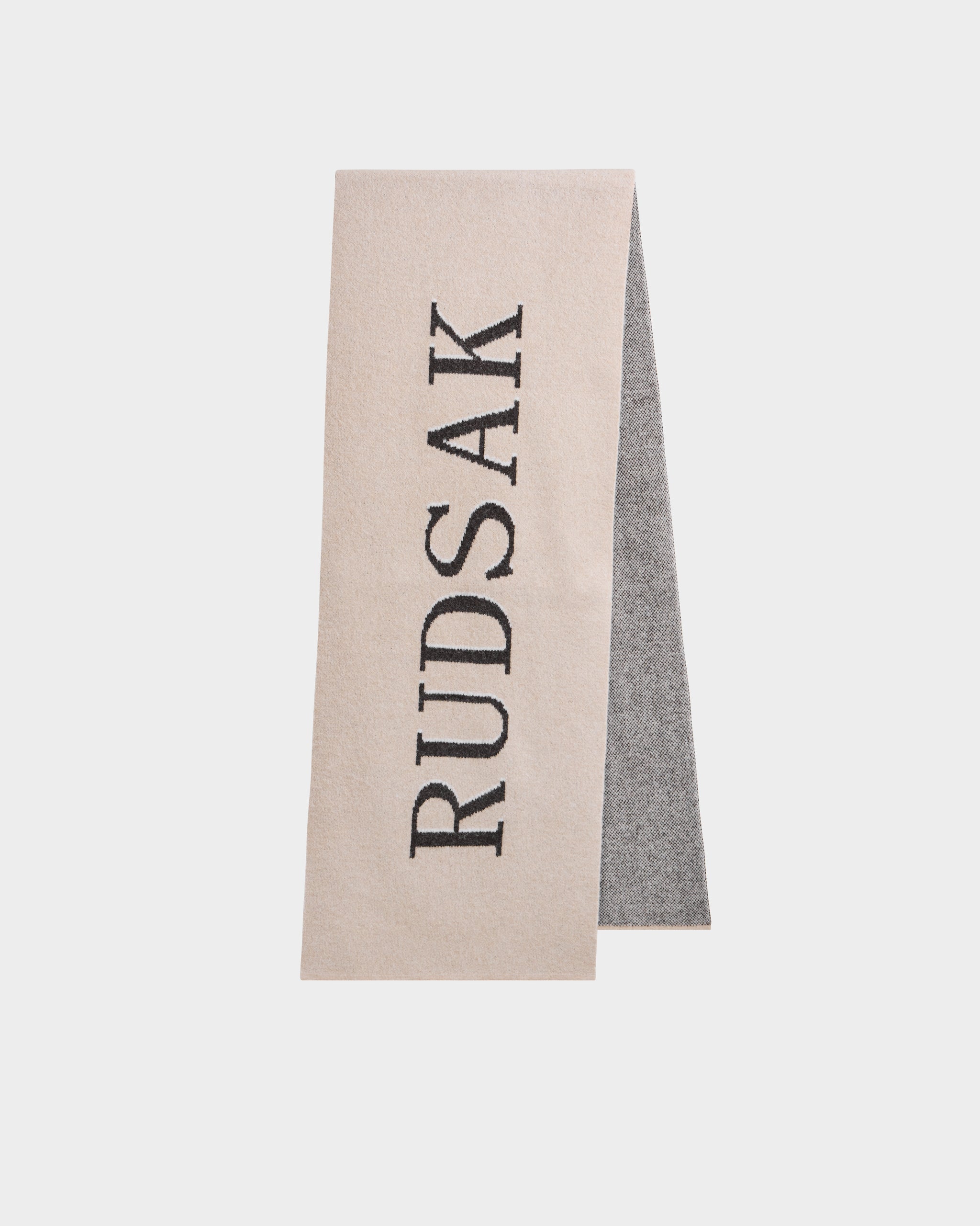The WYATT - 6425039 Vanilla men’s scarf by Rudsak features beige and gray hues with bold black RUDSAK lettering—an essential winter accessory, shown on a plain white background.