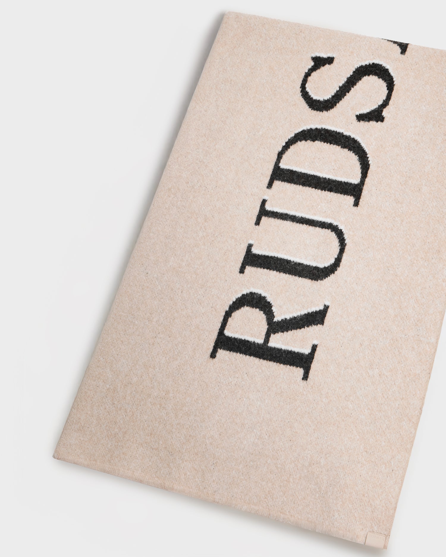 The WYATT - 6425039 Vanilla rug by Rudsak, in beige with black embroidered RUDSAK lettering, is photographed on a white background—an understated winter essential for adding seasonal style to any room.