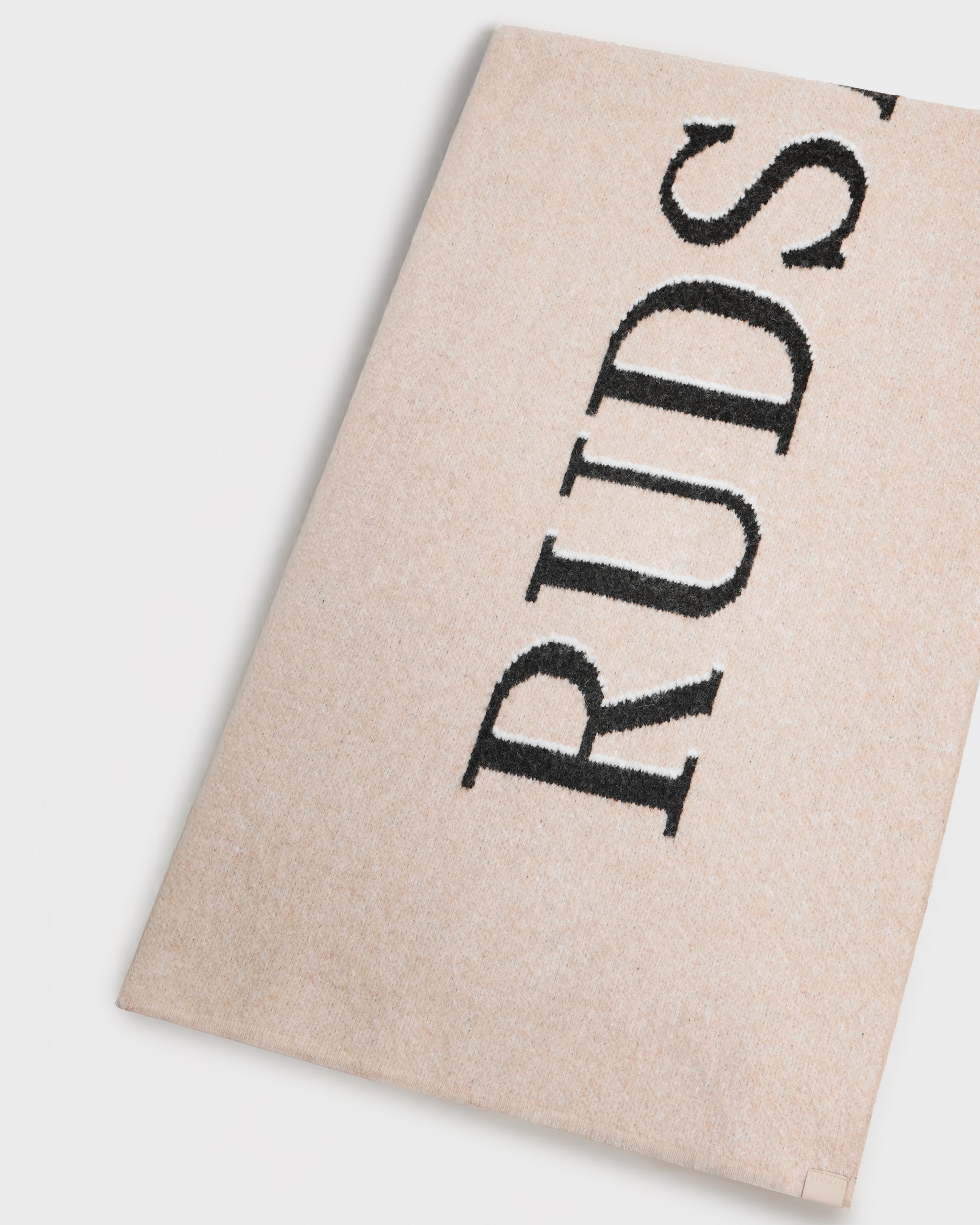 The WYATT - 6425039 Vanilla rug by Rudsak, in beige with black embroidered RUDSAK lettering, is photographed on a white background—an understated winter essential for adding seasonal style to any room.