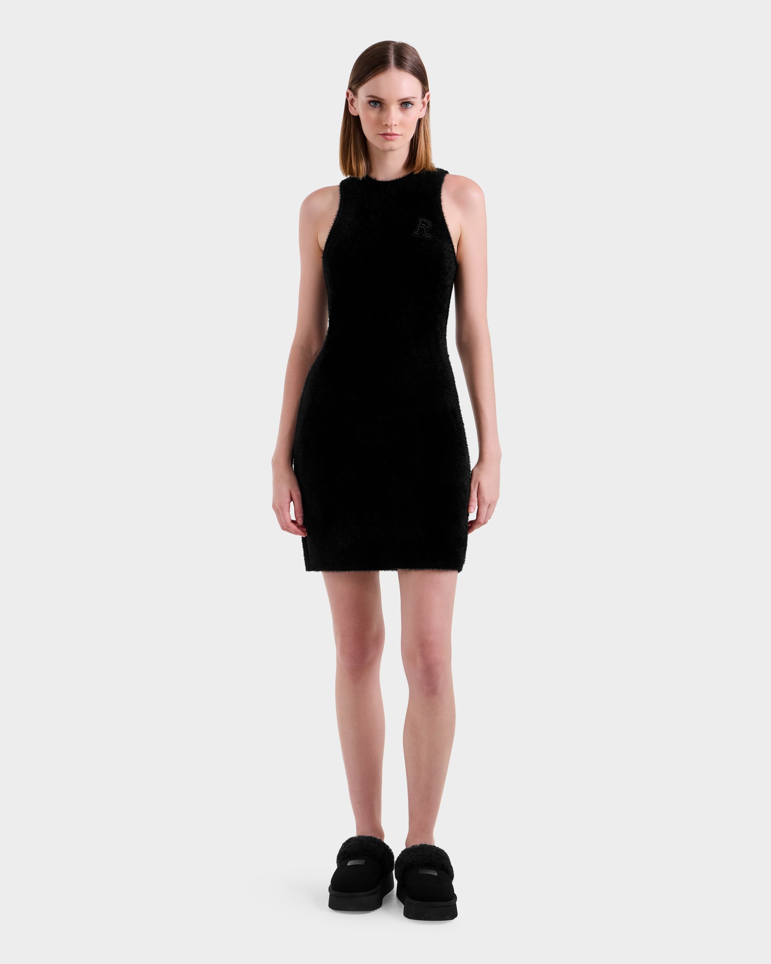 A woman faces forward in a Rudsak ZARAH - 8525696 Black fitted dress and black platform shoes, against a plain light gray background.