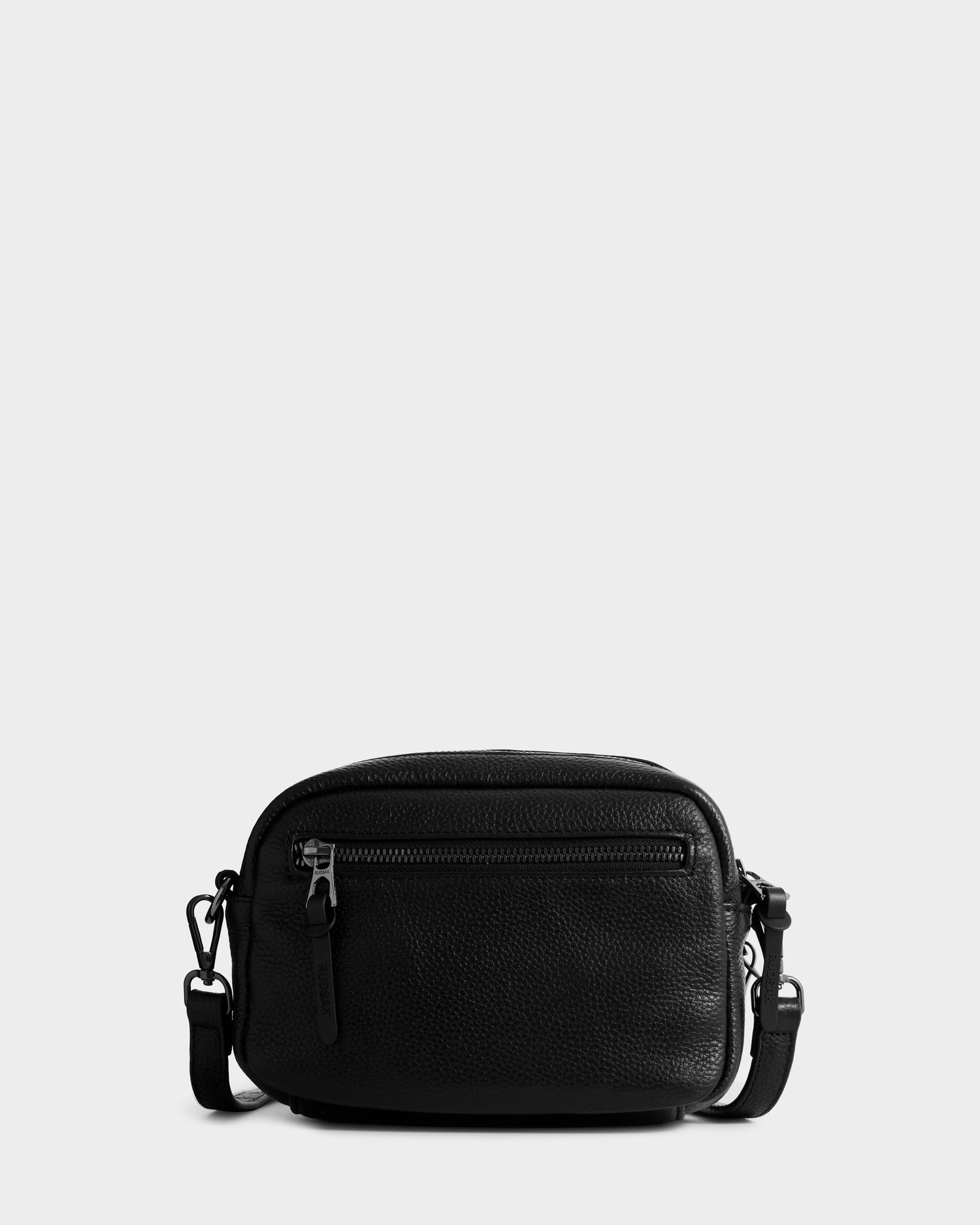The Rudsak ZOYA - L325015 Black is a small women’s pebbled leather crossbody bag with a textured finish, front zipper pocket, and adjustable strap, shown against a plain light gray background.