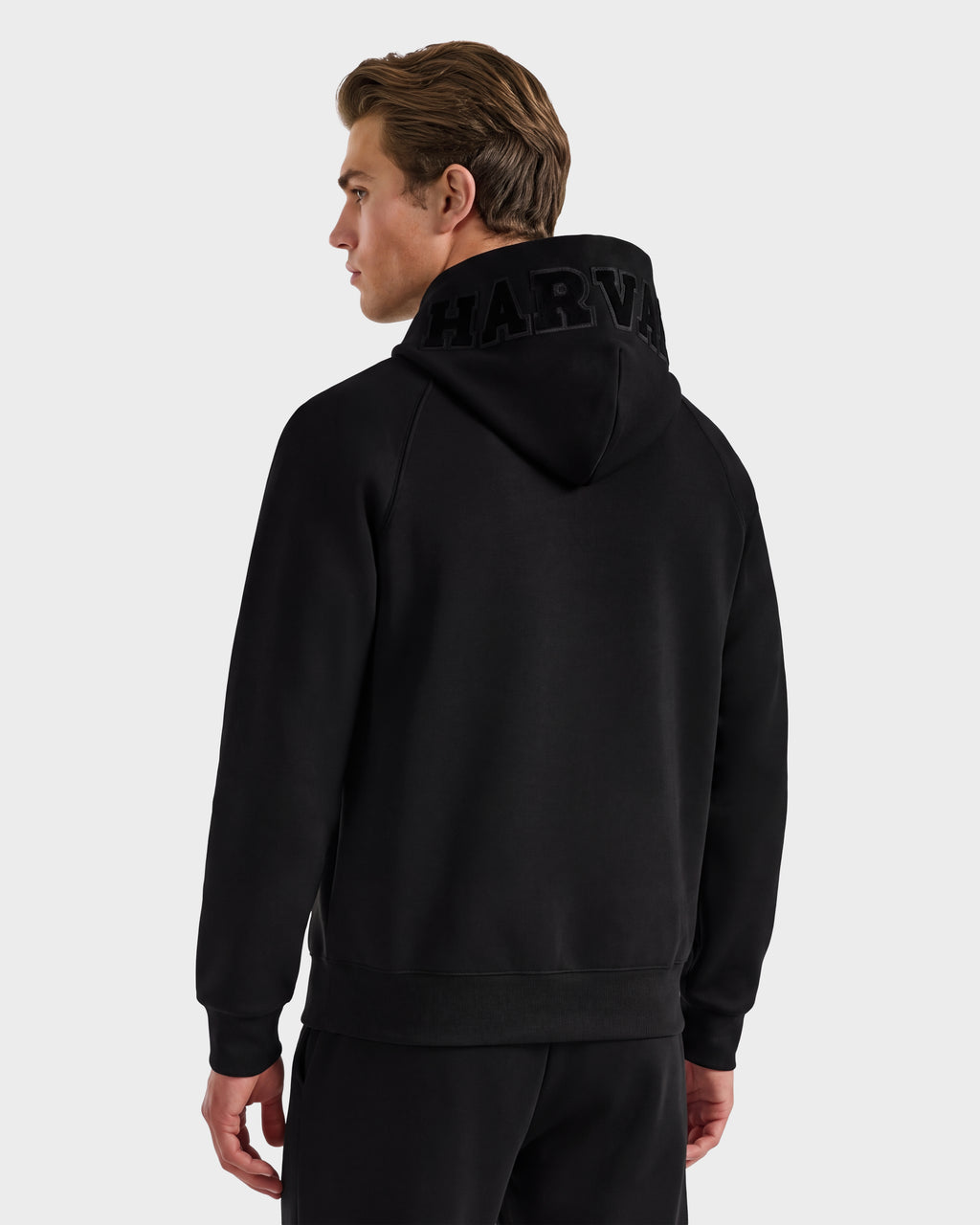 A person wearing a Rudsak BARRY HV - H525500 Black hoodie featuring the brand’s name in large letters on the hood, standing and facing away from the camera against a plain background.