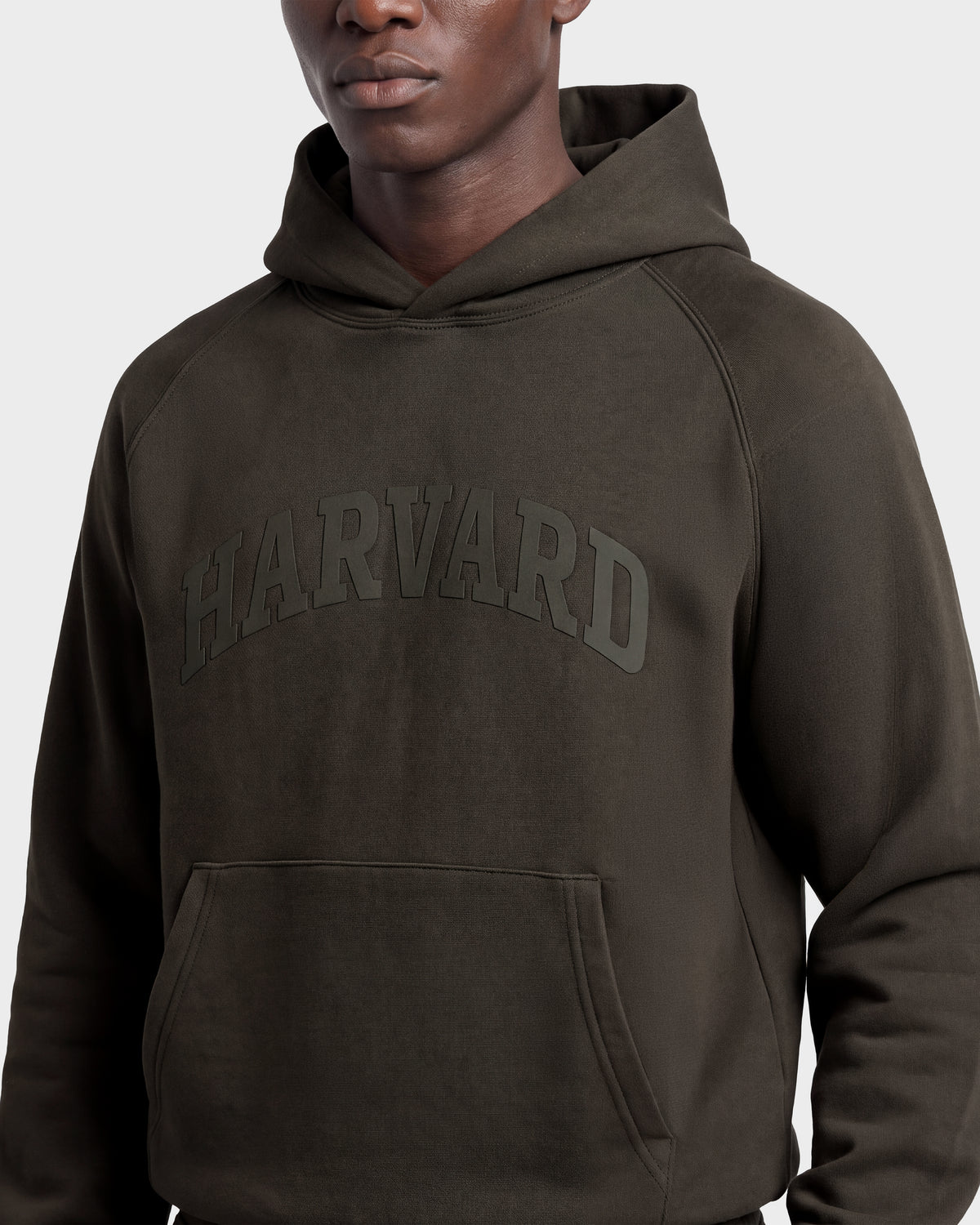 A person wearing the Rudsak BRIAR R HV - H525506 Olive hoodie with “HARVARD” printed in large letters on the front. The image shows their upper body against a plain background.