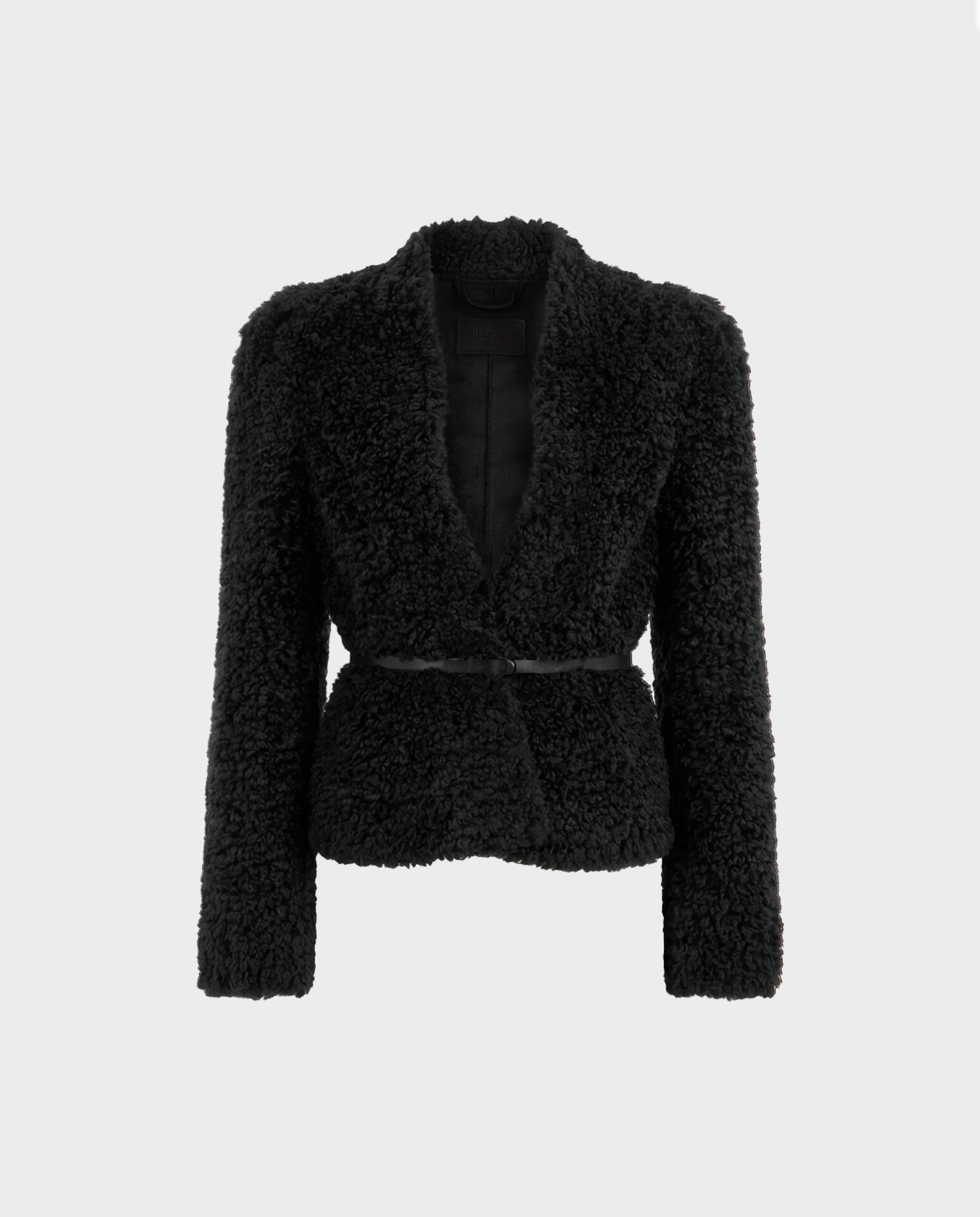The BRINLEY - 8126980 Black by Rudsak is a black, textured faux shearling teddy blazer featuring long sleeves, a shawl collar, and a subtle waist belt—shown against a plain white background, it’s the perfect cozy outer layer for effortless style.