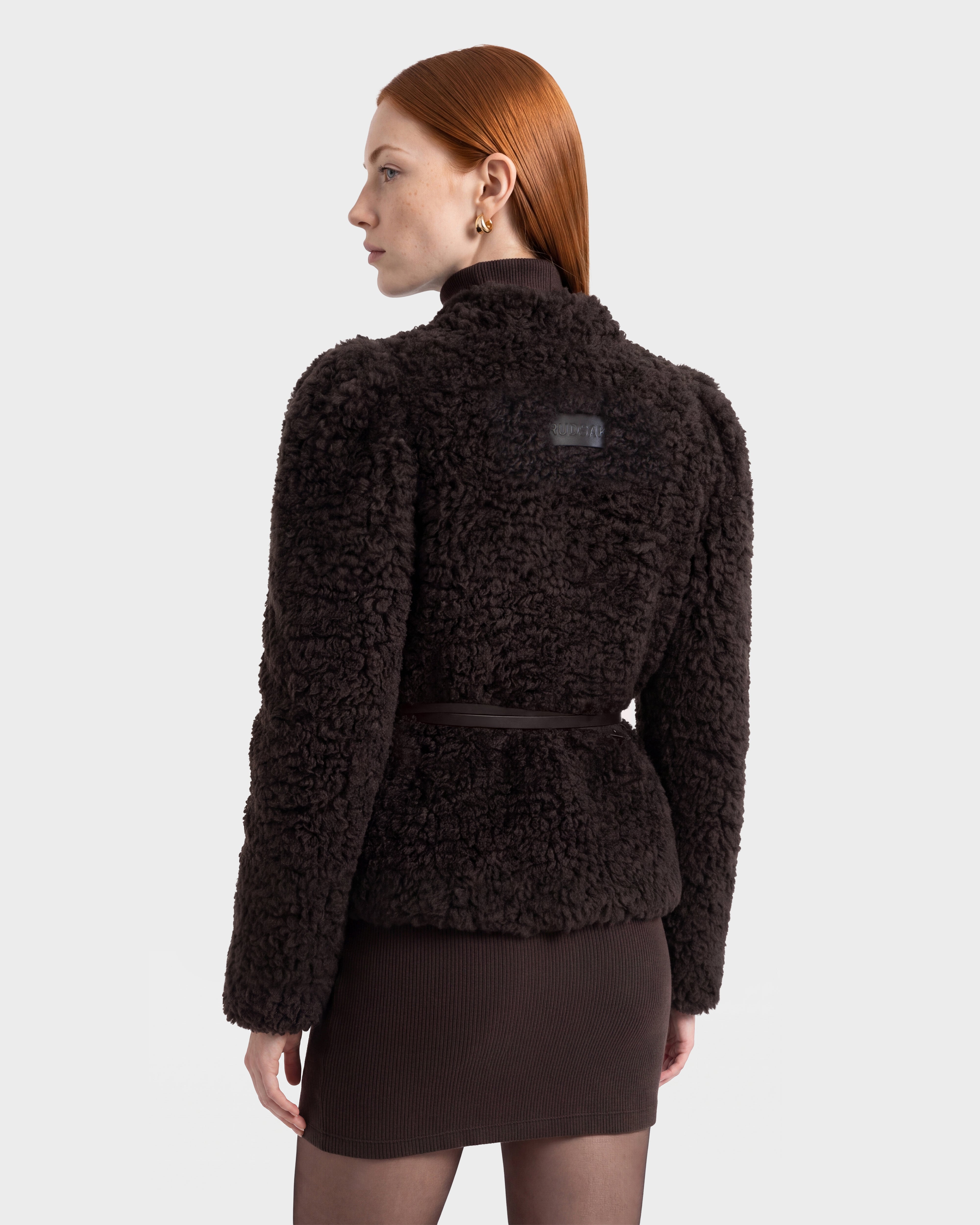 A person with straight red hair is seen from the back against a plain light background, wearing the Rudsak BRINLEY - 8126980 Espresso textured fleece jacket and a matching brown skirt.