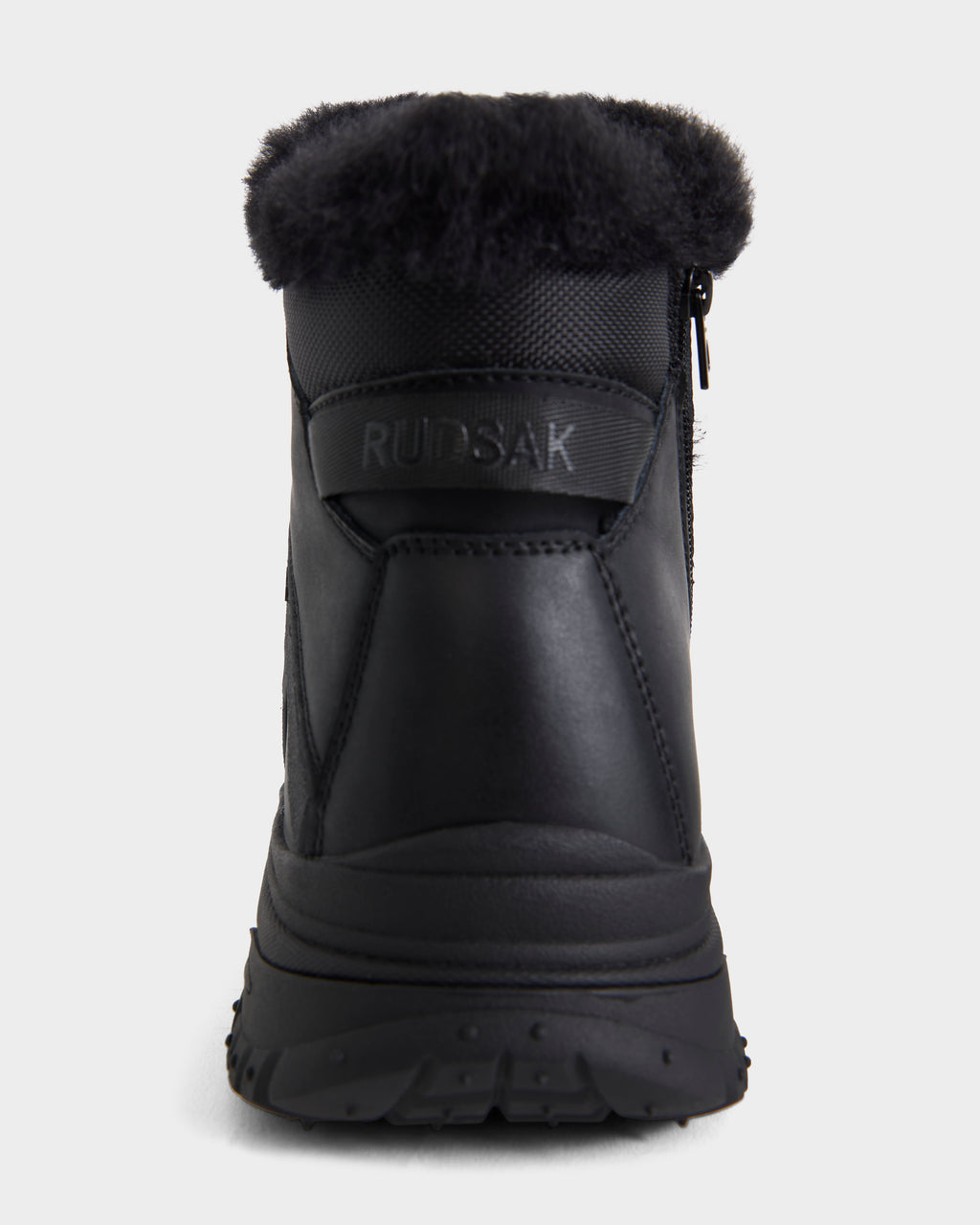 The BRYSON - 6226504 Black winter boot by Rudsak is shown from the back, featuring a fur collar, lace-up design, side zipper, and RUDSAK embossed on a leather patch above the heel.