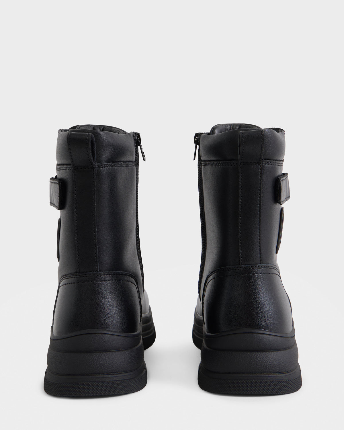 The DEREK - 6226506 Black by Rudsak is a pair of black ankle boots with thick soles, side zippers, and a smooth finish, shown from the back on a plain white background.