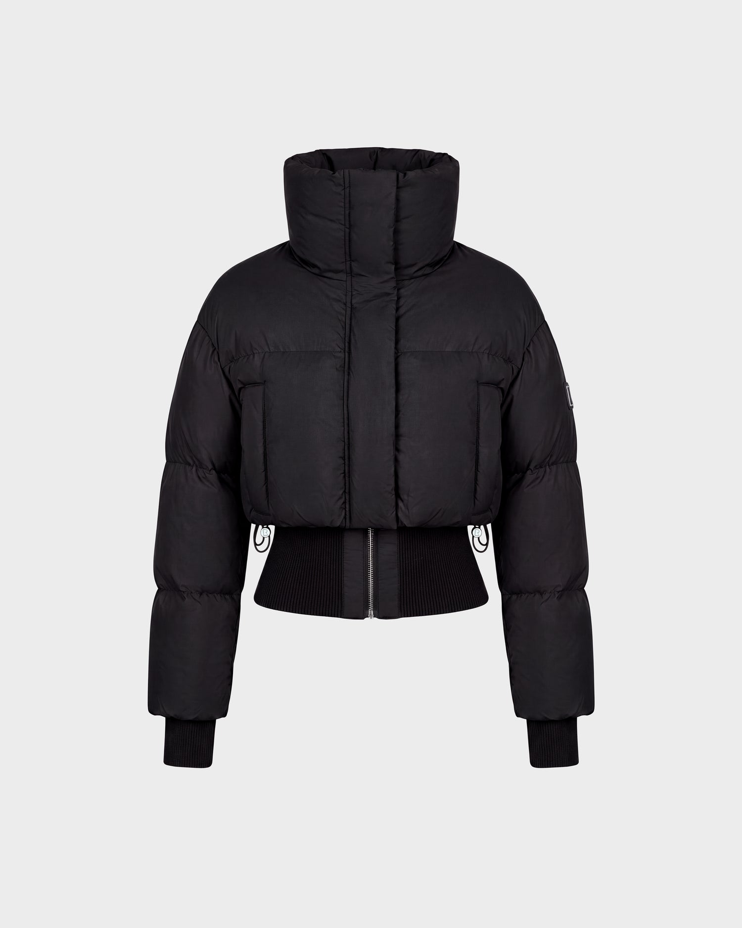 The Rudsak DONYA - 8126516 Black is a black cropped puffer jacket featuring a high collar, long sleeves, ribbed cuffs, and a front zipper, shown against a plain light gray background. Now available for pre-order; expected to ship by September 15th.