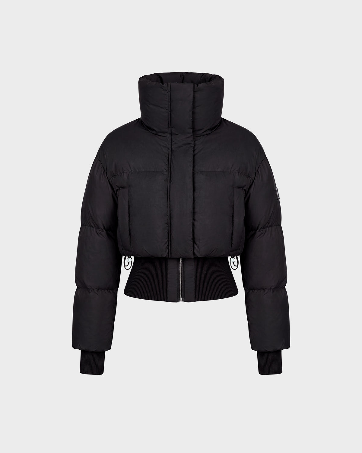 The Rudsak DONYA - 8126516 Black is a black cropped puffer jacket featuring a high collar, long sleeves, ribbed cuffs, and a front zipper, shown against a plain light gray background. Now available for pre-order; expected to ship by September 15th.