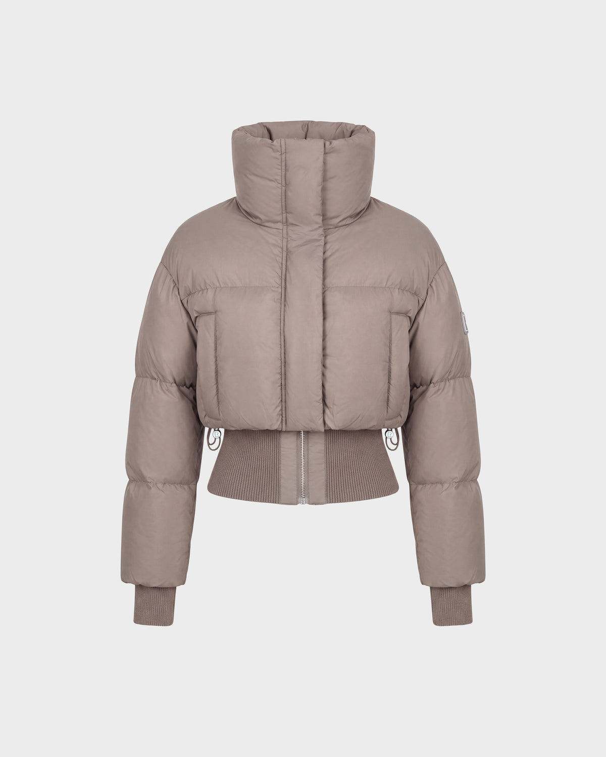 The Rudsak DONYA - 8126516 Cement is a taupe-colored, cropped women’s down puffer jacket made with RDS-certified down, featuring a high collar along with ribbed cuffs and hem, shown against a plain white background.