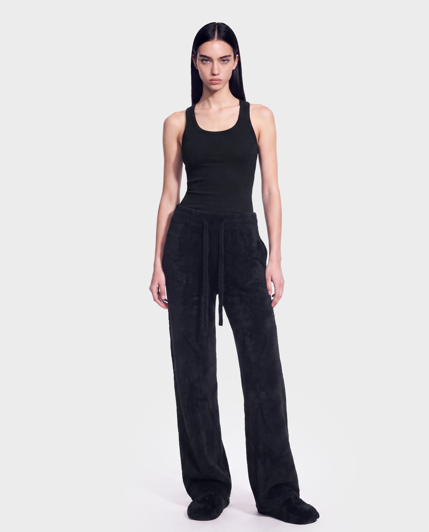 A person stands facing forward against a plain light gray background, wearing the Rudsak GENESIS - 8526506 Black sleeveless tank top and loose drawstring black pants.