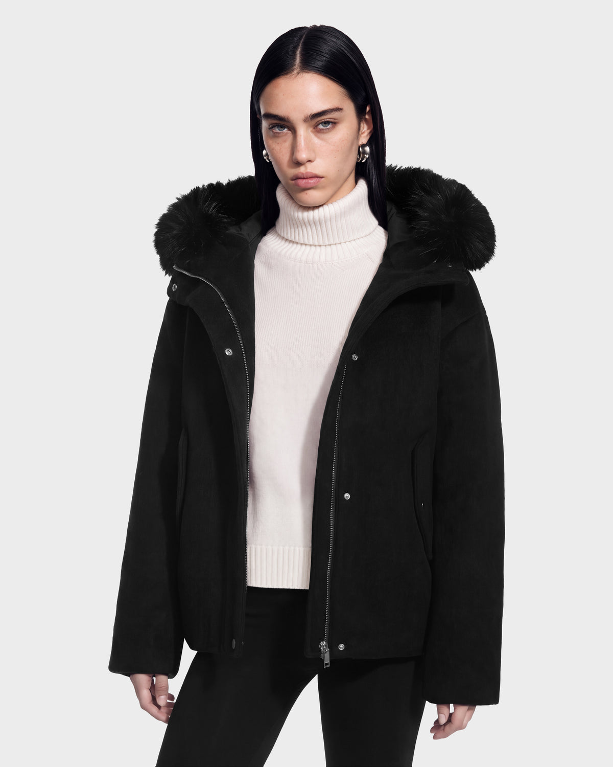 A model wears a black Rudsak HAZEL - 8126981 Black wool-blend winter coat with a detachable faux-fur hood over a white turtleneck sweater.