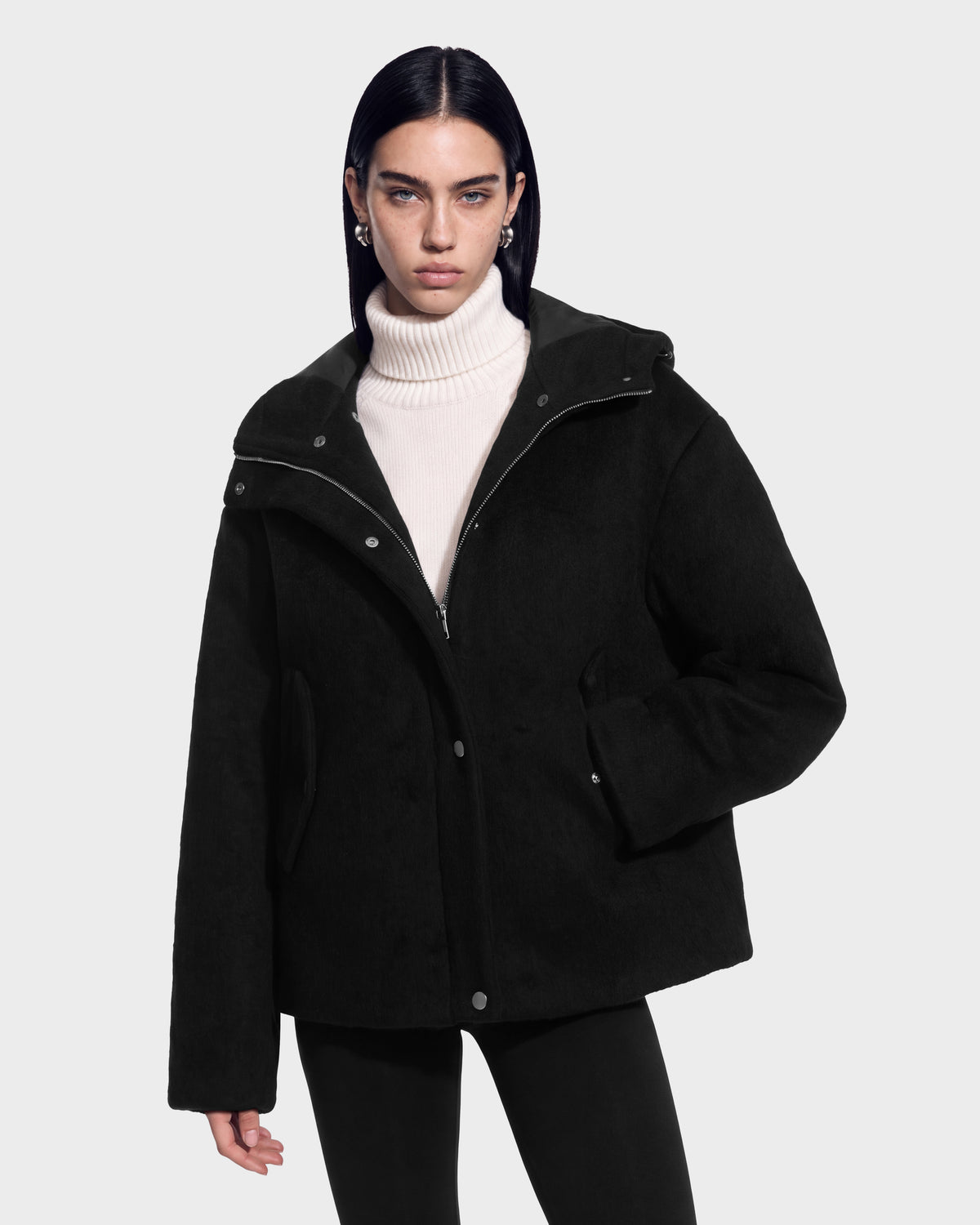 A model wears a black Rudsak HAZEL - 8126981 wool-blend winter coat with a detachable faux-fur hood over a cream-colored turtleneck sweater.