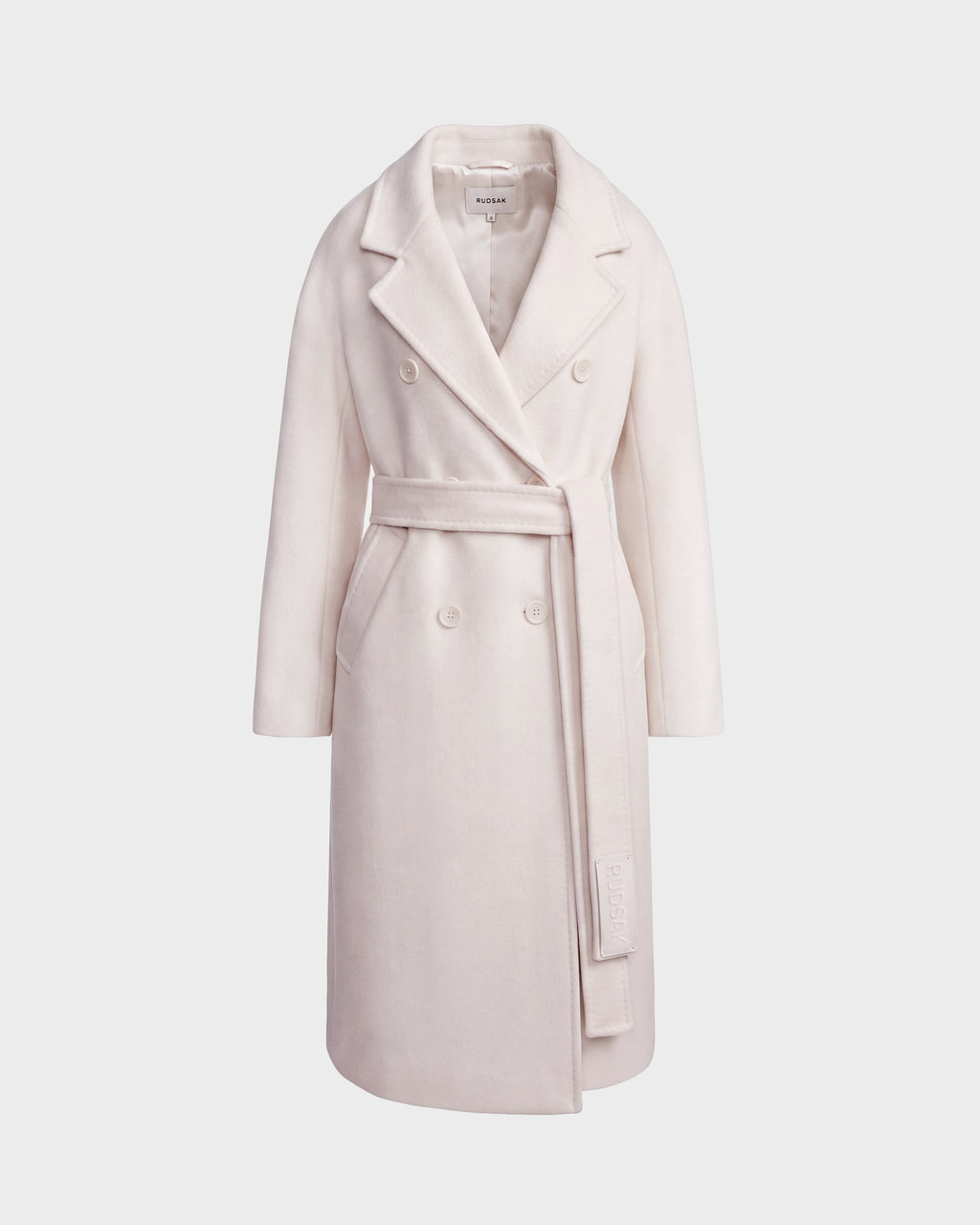 The Rudsak KOURT W - 8124702 Vanilla is a long, light beige women’s wool coat featuring a wide lapel collar and a matching belt tied at the waist, shown against a plain white background.