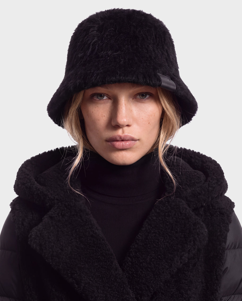 A person wearing a black nylon-blend bucket hat and a MAIE - 8426517 Black hooded coat with a fleece lining.
