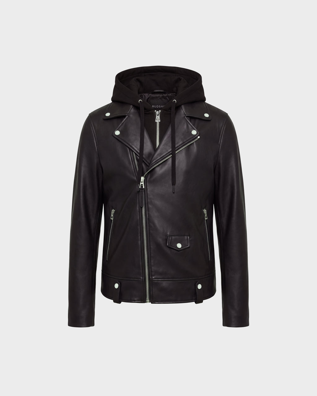 The MANUS - 6124600 Black men’s leather moto jacket by Rudsak features black leather construction with silver zippers and buttons, an asymmetrical front zip, two zippered pockets, a flap pocket on the front, and a removable hooded dickie for added versatility. The background is light gray.