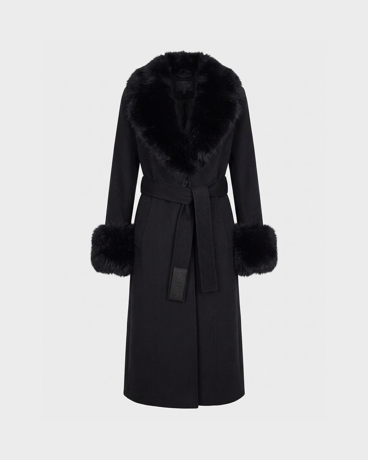 The MARILLA WL - 8126737 Black coat by Rudsak is a long black wool piece featuring a wide faux fur collar and matching fur cuffs. This tailored outerwear includes a tie belt at the waist and showcases a smooth, elegant silhouette, presented against a plain light background.