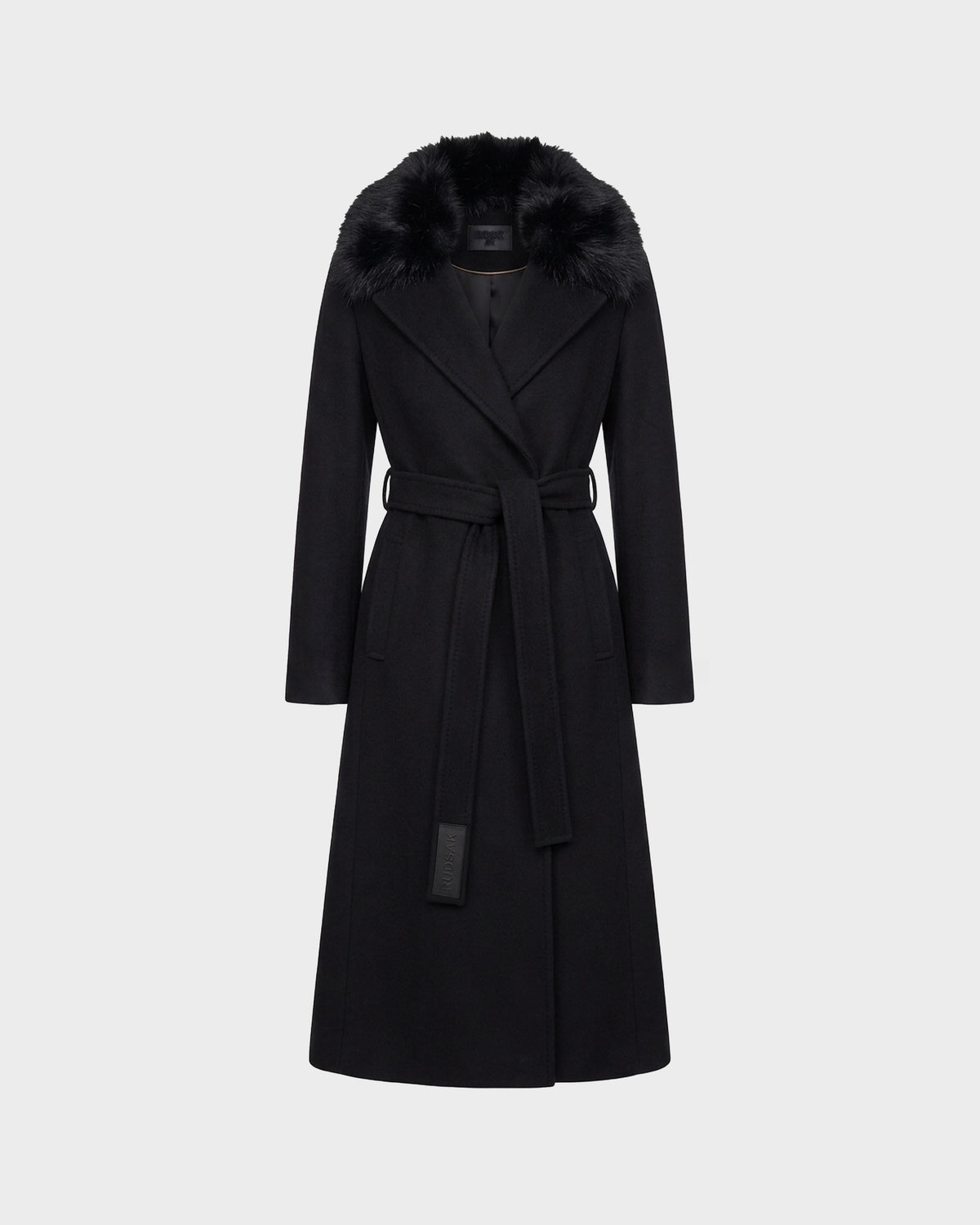 The Rudsak MEL - 8126525 Black is a long tailored wool coat in classic black, featuring a wide removable faux fur collar, long sleeves, belted waist, and two side pockets, displayed against a plain light gray background.