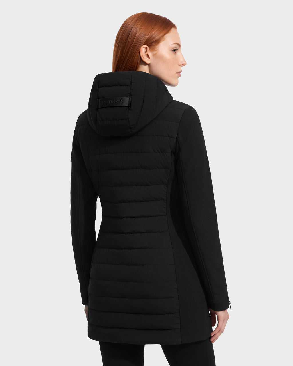 A person seen from the back wearing a black MERINA - 8125056 hooded, quilted down jacket by Rudsak.