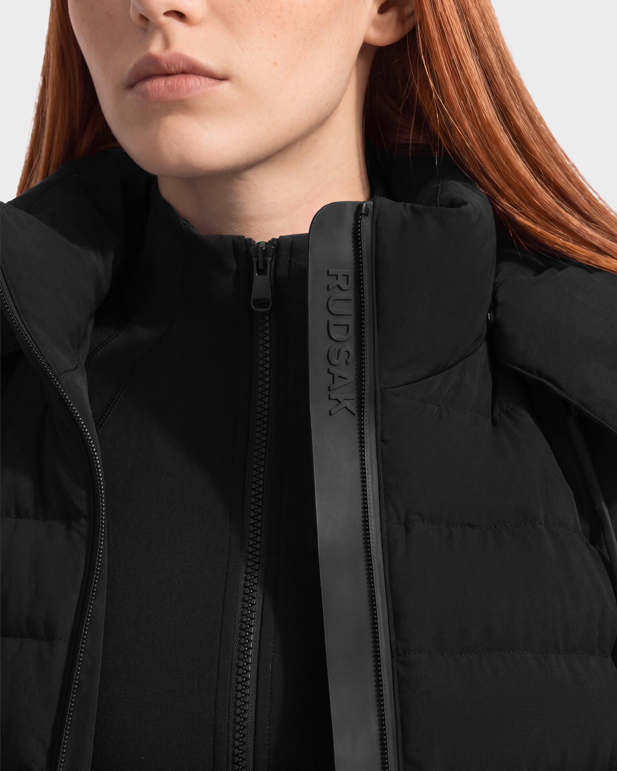 Close-up of a person wearing a black quilted MERINA - 8125056 transitional jacket with a branded zipper placket.