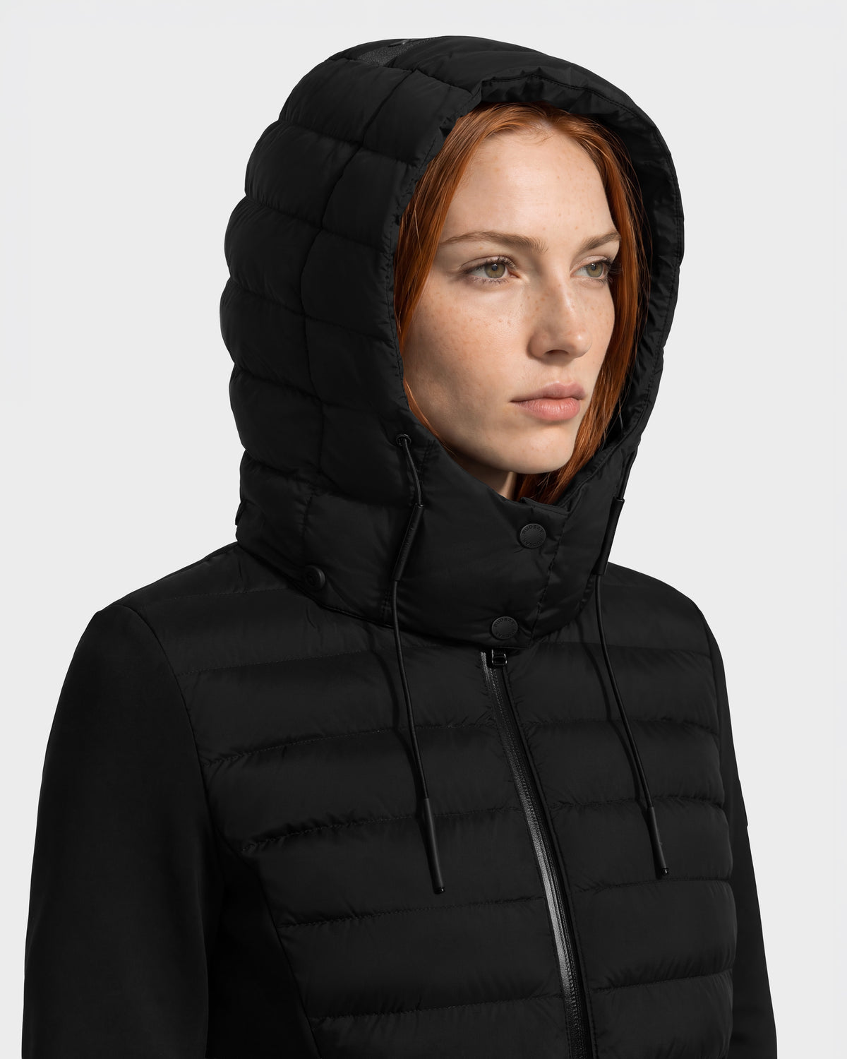 A person wearing a black Rudsak MERINA - 8125056 hooded, quilted down jacket with a front zipper.