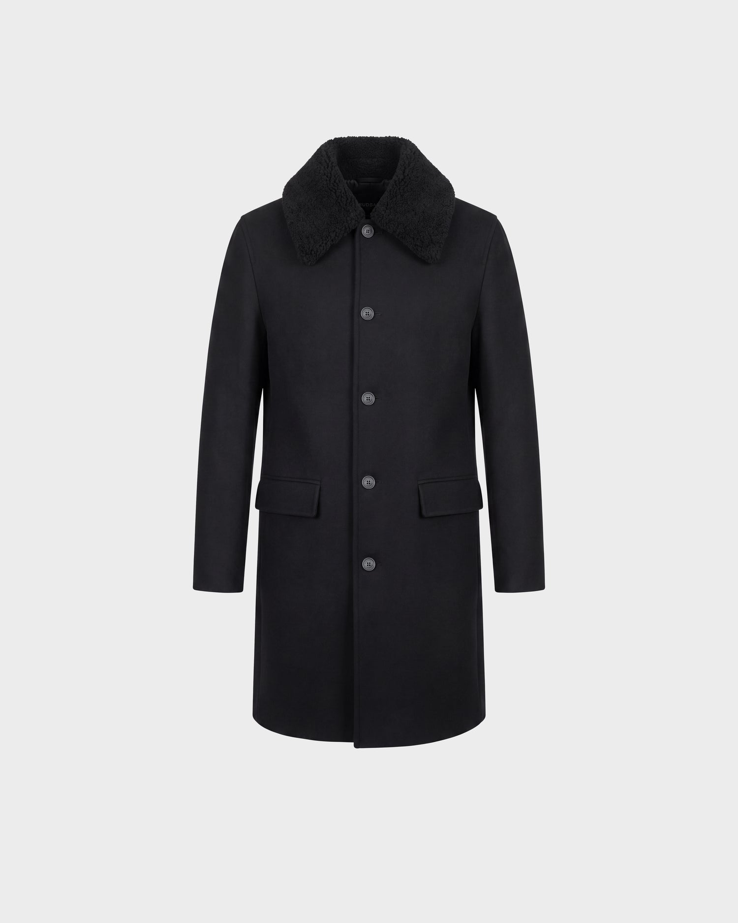 The NICO - 6126717 Black by Rudsak is a men’s knee-length long wool coat in black, featuring a button-down front, large side pockets, and a textured removable faux-shearling collar. It is displayed against a plain light gray background.