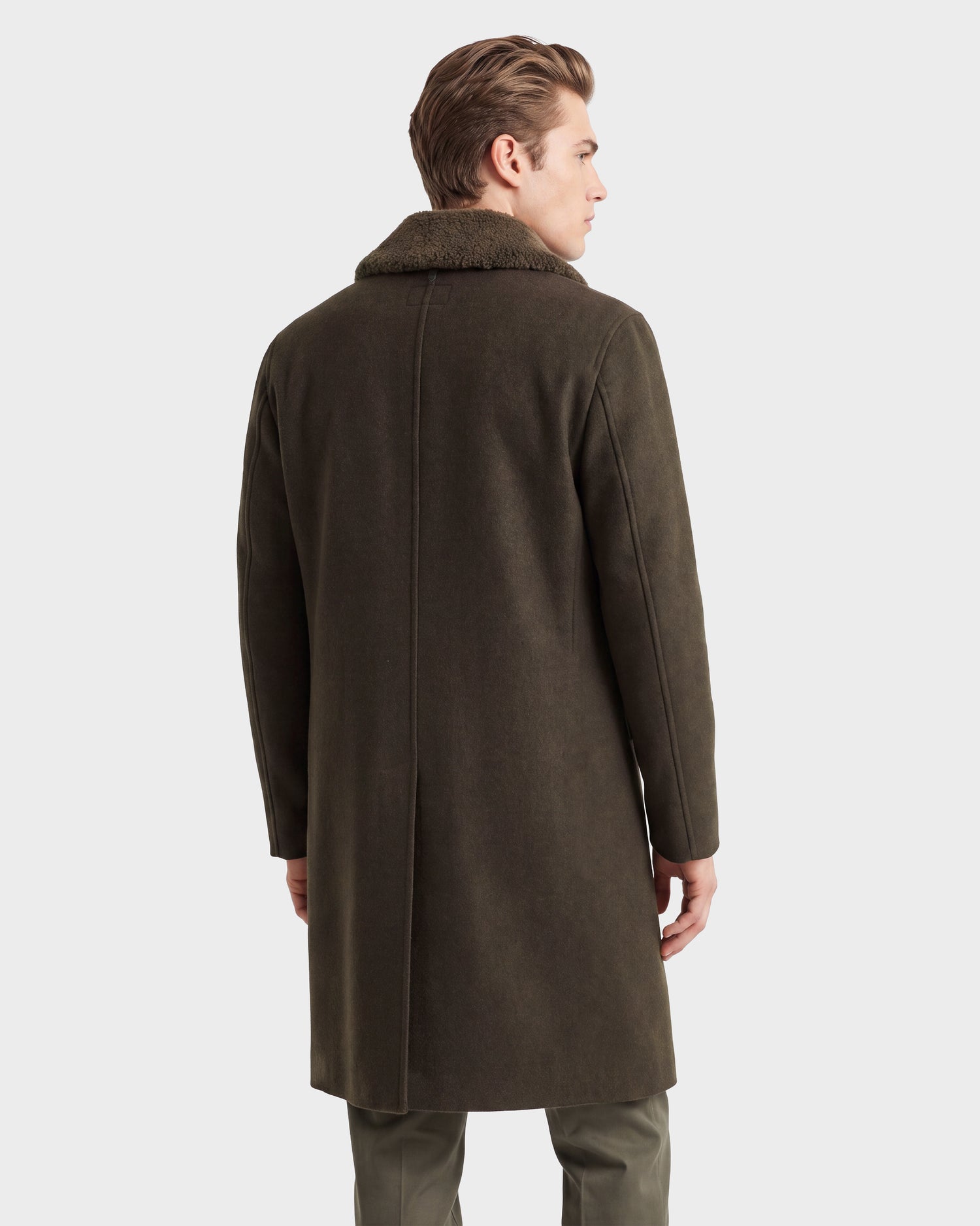A man with light brown hair, wearing the Rudsak NICO - 6126717 Olive wool blend overcoat with a fur collar, stands facing away against a plain white background—a perfect example of transitional layering.
