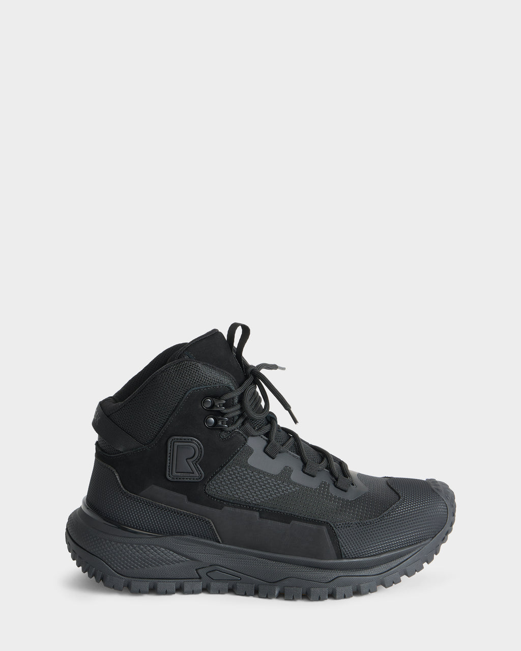 The Rudsak REXON - 6226503 Black is a high-top sneaker featuring a textured sole, lace-up front, mesh and synthetic panels, and a bold R logo on the ankle, shown from the side against a plain white background.