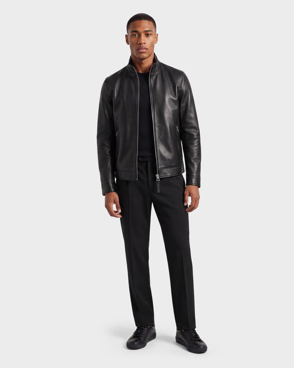 A man stands facing forward, wearing the Rudsak STEVEN - 6124541 Black leather jacket, paired with a black shirt, black pants, and black shoes against a plain white background.
