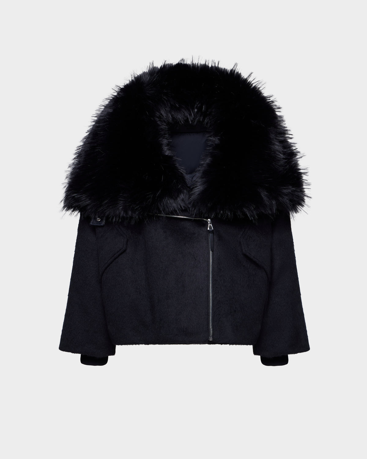 The Rudsak ZARIA - 8126999 Black features an oversized winter puffer design with long sleeves, an asymmetrical front zipper, and a removable faux-fur collar, shown on a plain white background.