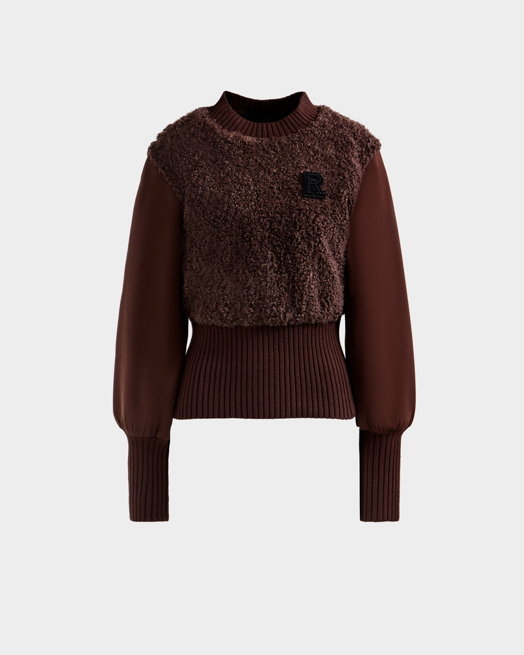 The FLORENCE - 8525546 Mocha sweater by Rudsak features a brown, long-sleeve design with a textured fuzzy front, ribbed cuffs and waist, balloon sleeves, and a small black R patch on the chest. Shown against a plain light gray background.
