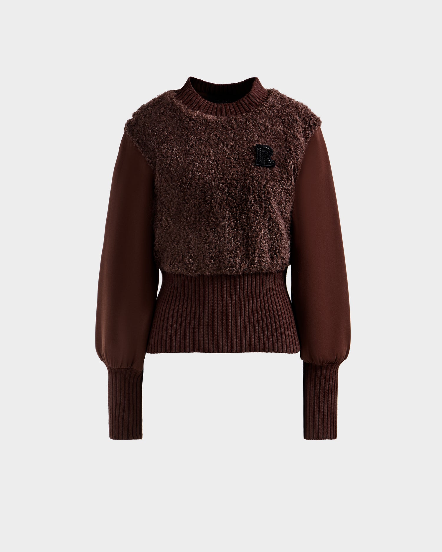 The FLORENCE - 8525546 Mocha sweater by Rudsak features a brown, long-sleeve design with a textured fuzzy front, ribbed cuffs and waist, balloon sleeves, and a small black R patch on the chest. Shown against a plain light gray background.