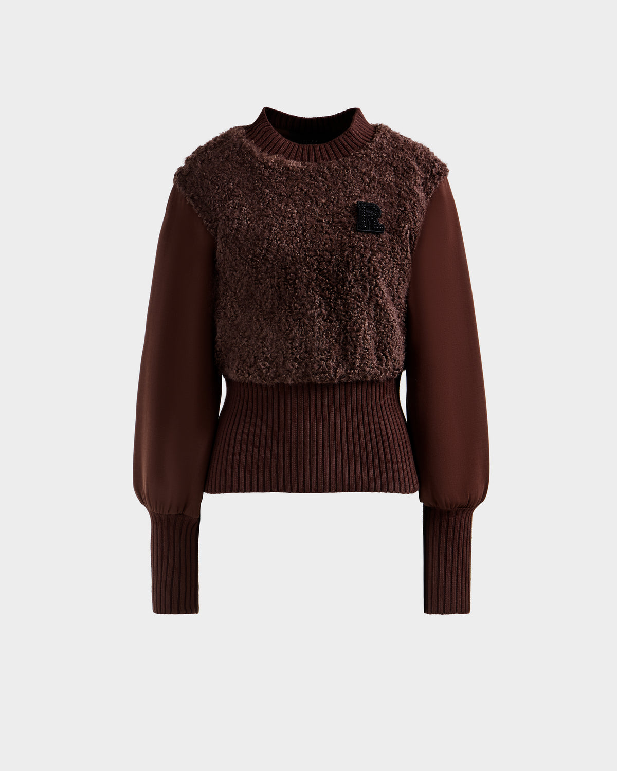 The FLORENCE - 8525546 Mocha sweater by Rudsak features a brown, long-sleeve design with a textured fuzzy front, ribbed cuffs and waist, balloon sleeves, and a small black R patch on the chest. Shown against a plain light gray background.