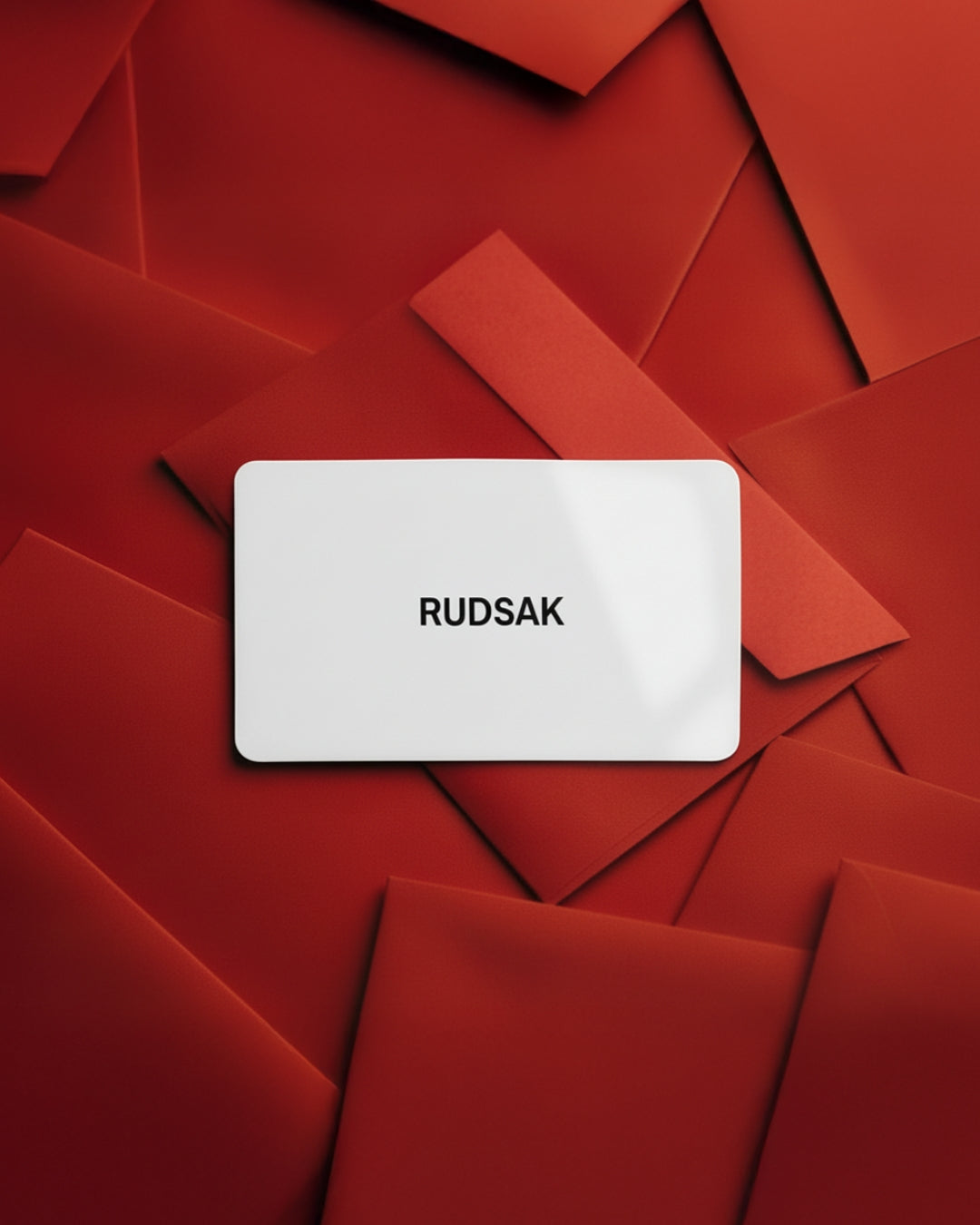A white Rudsak card sits on red envelopes—ideal as a VIRTUAL GIFT CARD - English that lets you pick your delivery date or enjoy fast, convenient email delivery.